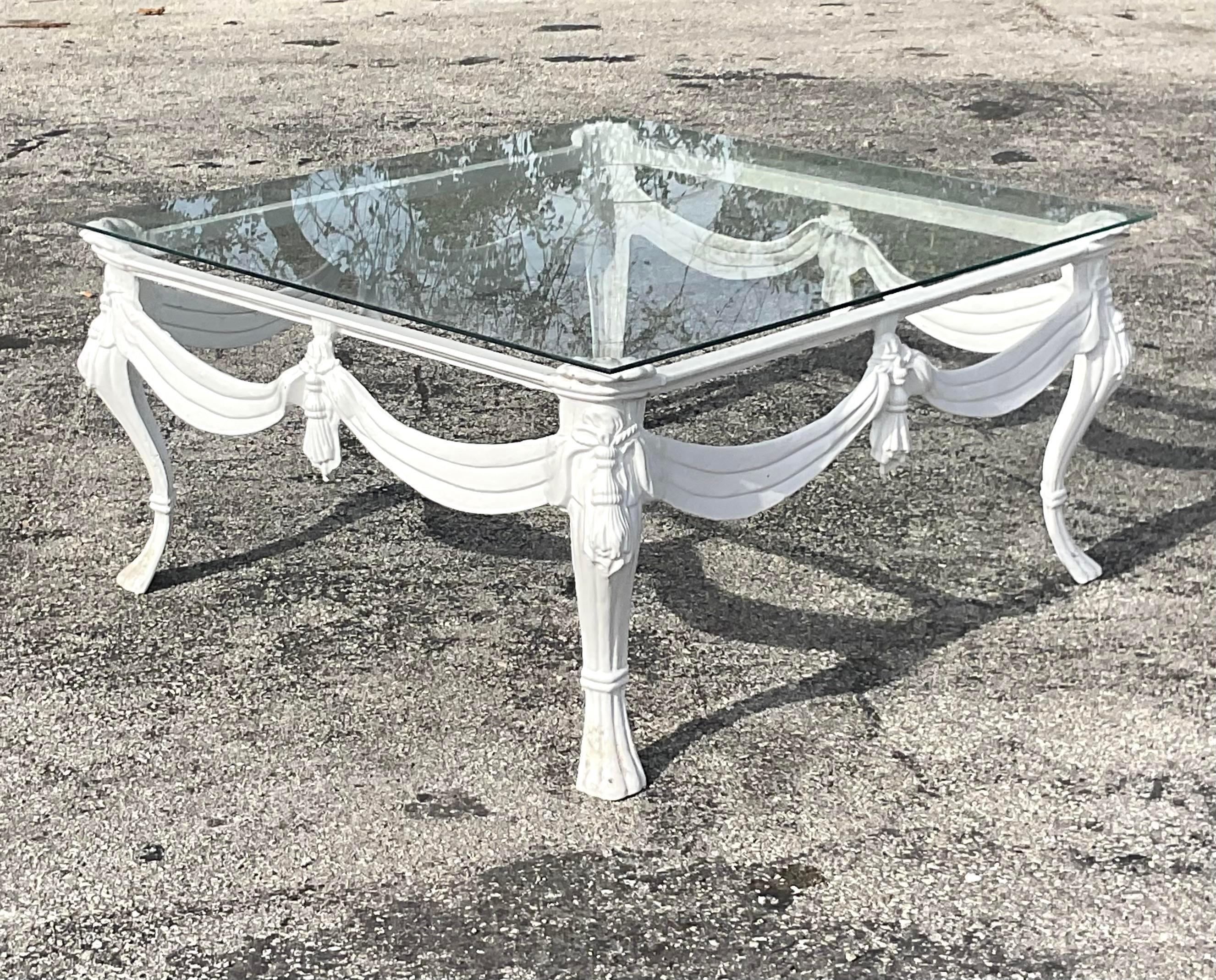 A fabulous vintage Regency outdoor coffee table. A lacquered wrought iron frame with gorgeous swag detail. Glass rests on top of the square frame. Acquired from a palm Beach estate.