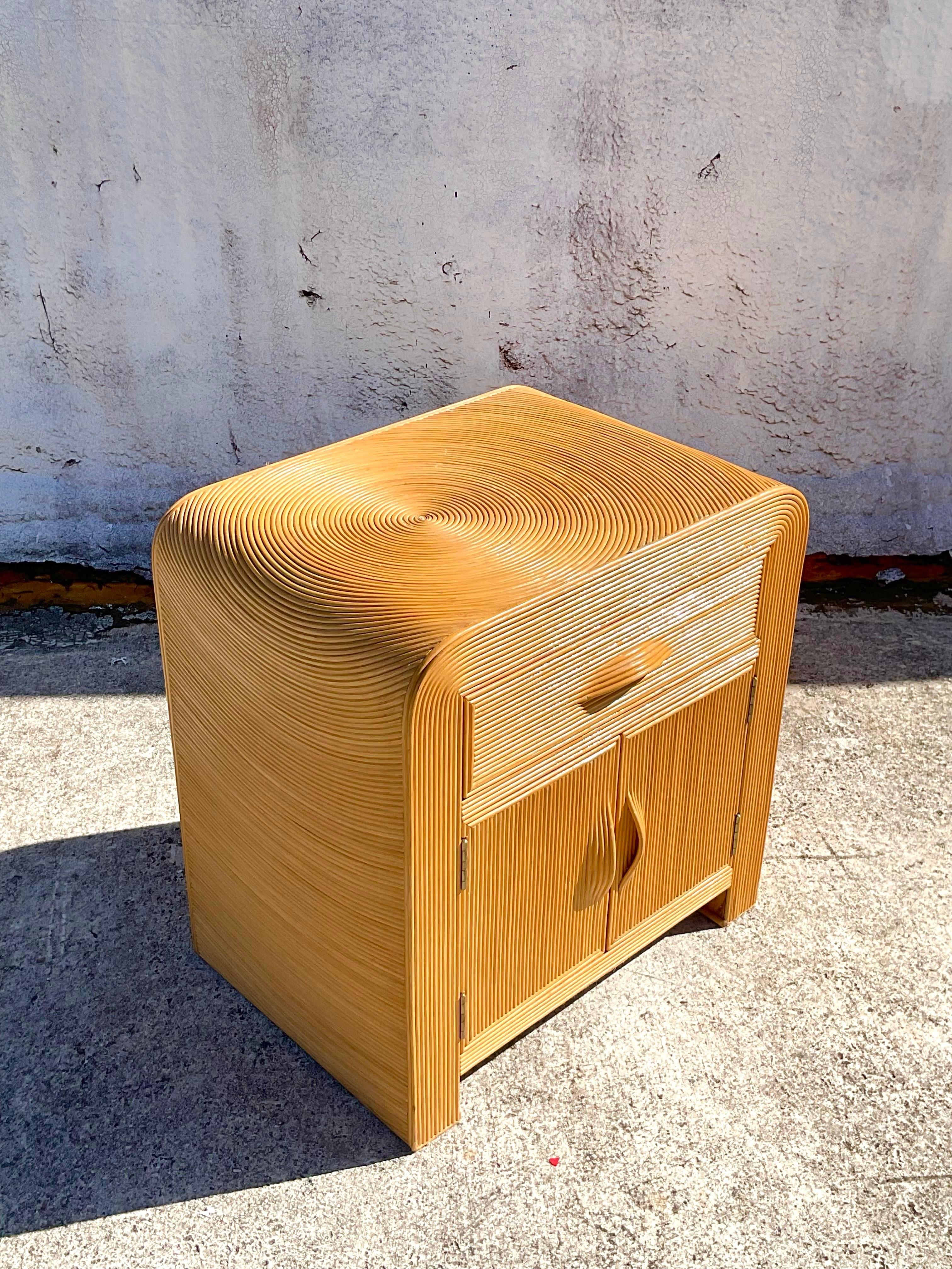 A lovely vintage single waterfall nightstand made of split reed with a spiral design drawer and cabinet doors. After Gabriella Crespi. Iconic integrated handles for the drawers and cabinet doors. Acquired at a Palm Beach estate. l