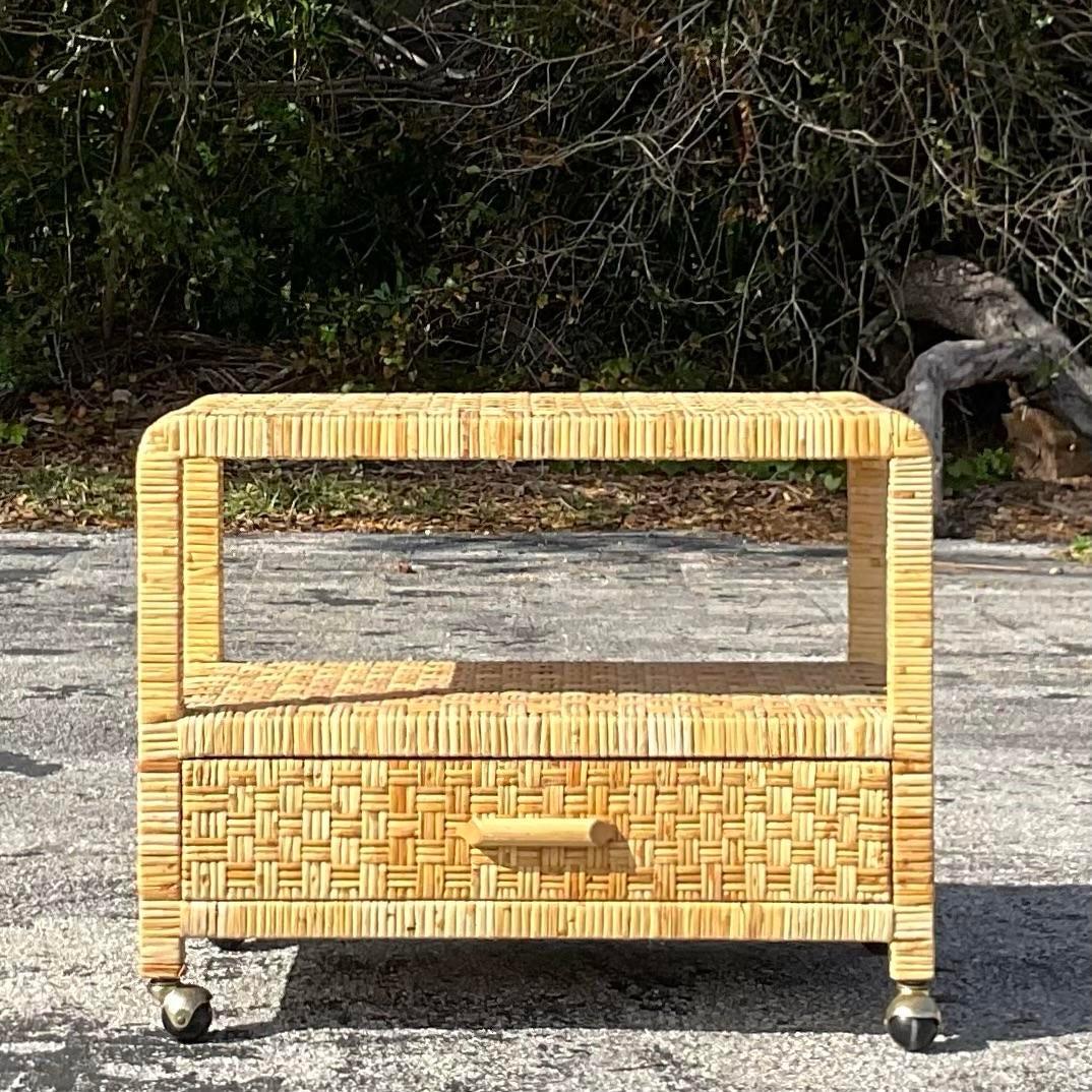 A wonderful vintage television stand made from woven rattan with a shelf and drawer. Conveniently set on four wheels for easy mobility. Acquired at a Palm Beach estate. l