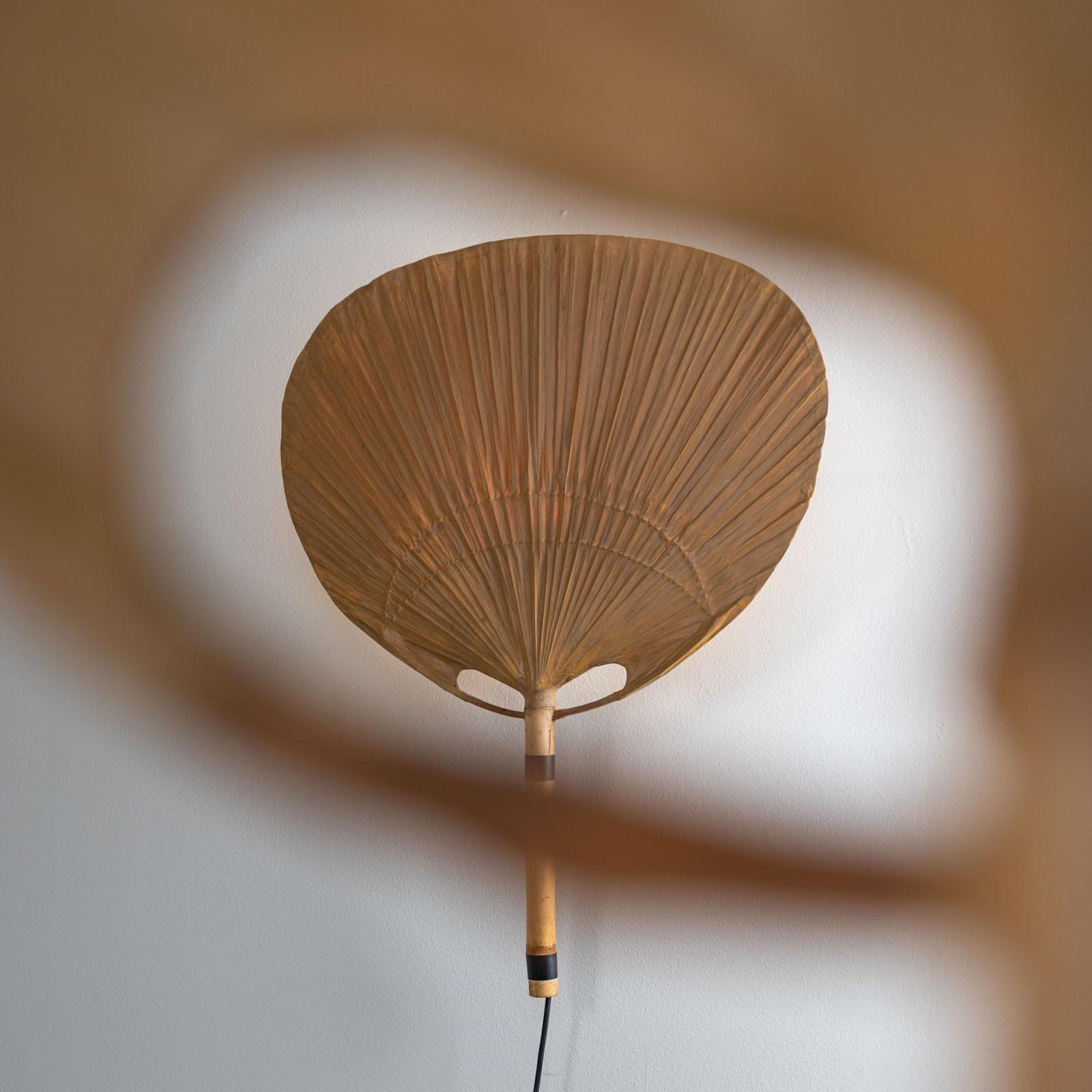 Large “Uchiwa III” wall lamps, designed by Ingo Maurer for Design M. The fan-shaped lights are made of lightweight bamboo and delicate rice paper, giving them a refined yet organic appearance. They emit a soft, indirect light that bathes the room in