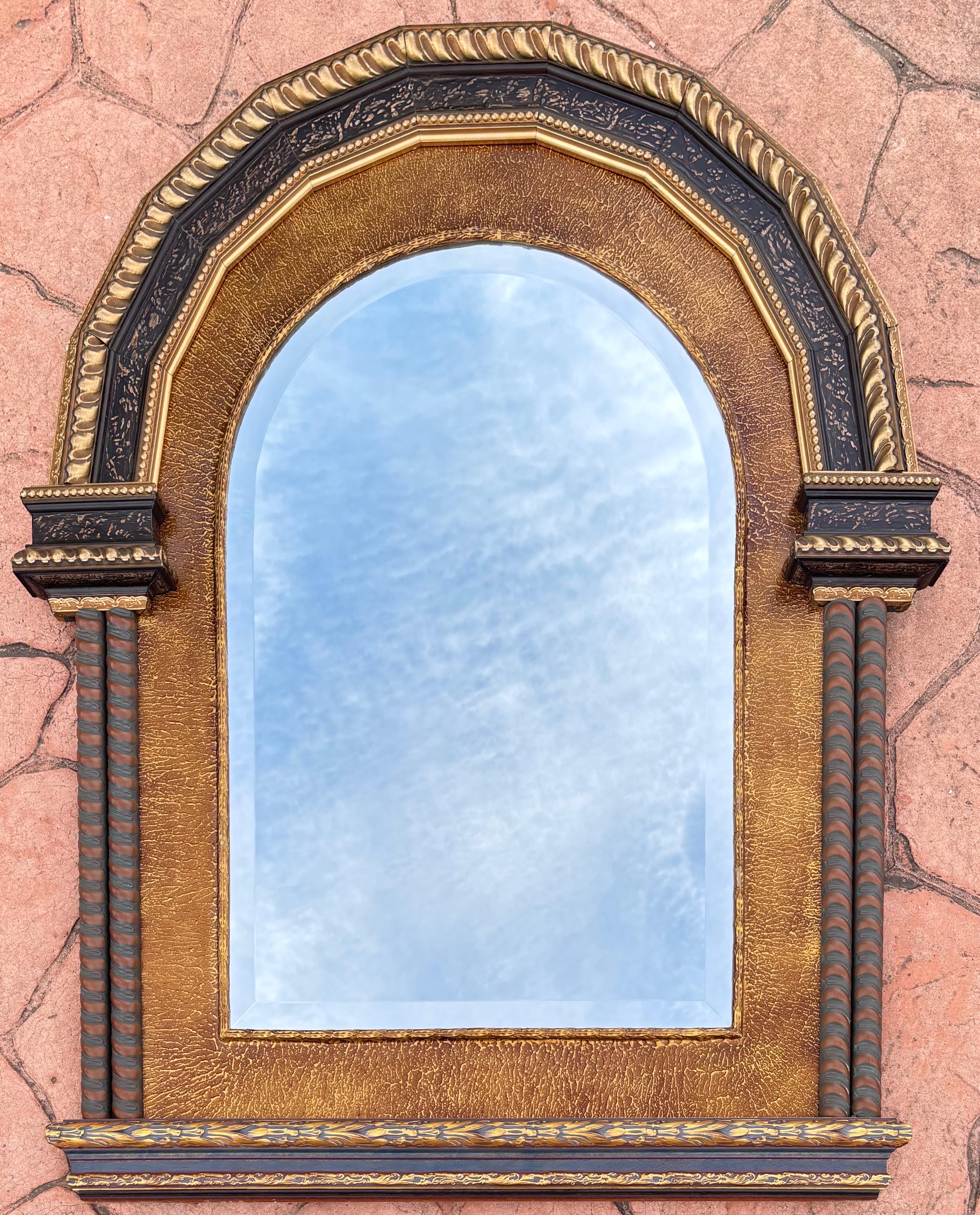 Elegant miroir néoclassique de la fin du 20e siècle présentant un cadre architectural richement détaillé, combinant magnifiquement le bois sculpté, le plâtre moulé et des finitions dorées raffinées. La silhouette arquée s'inspire des portails