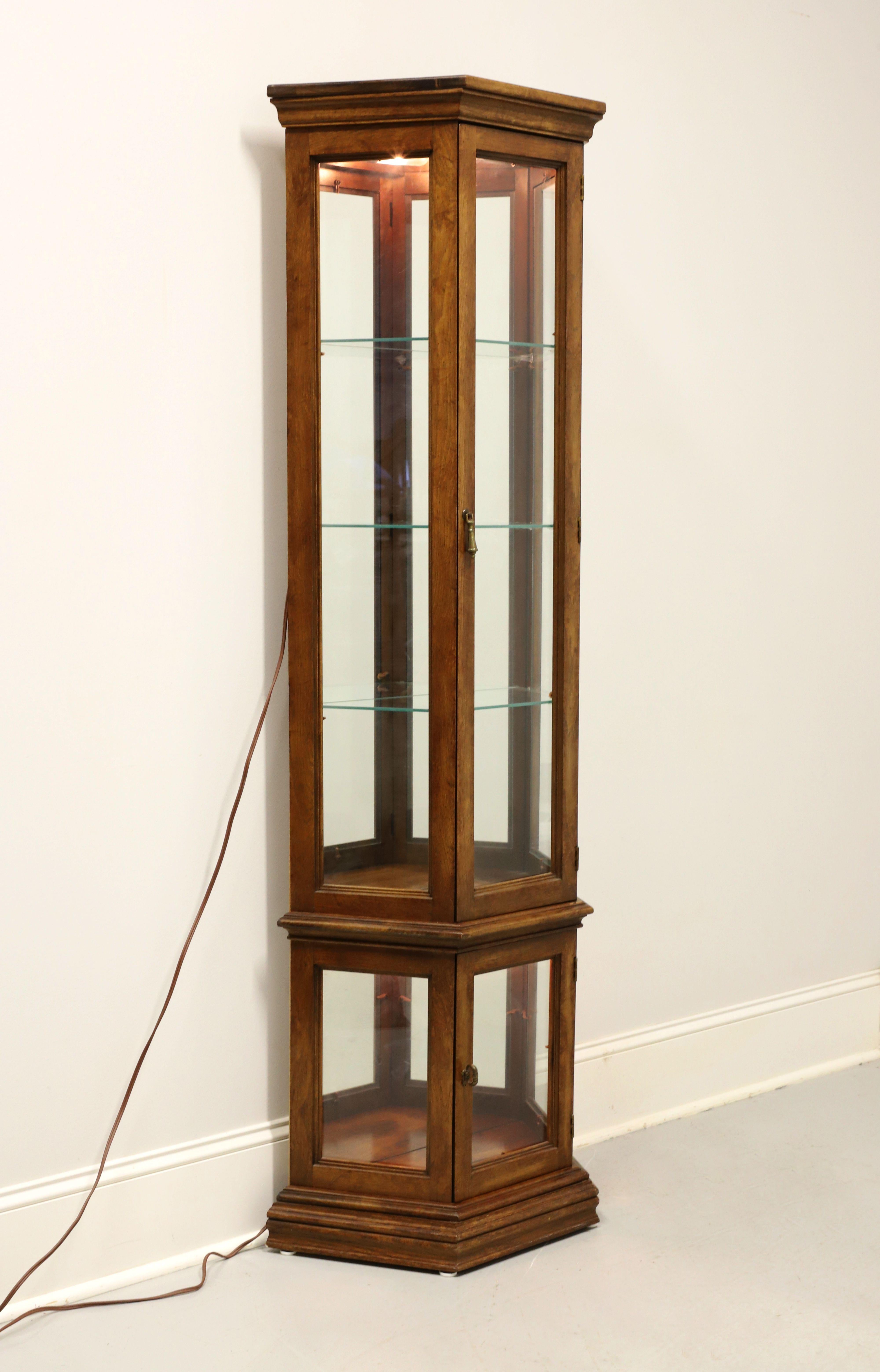 A Traditional style curio display cabinet, unbranded, similar quality to Thomasville or Tomlinson. Walnut with a slightly distressed finish, isosceles trapezoid shape, brass hardware, crown moulding to top, bevel edge to top of lower cabinet, and a
