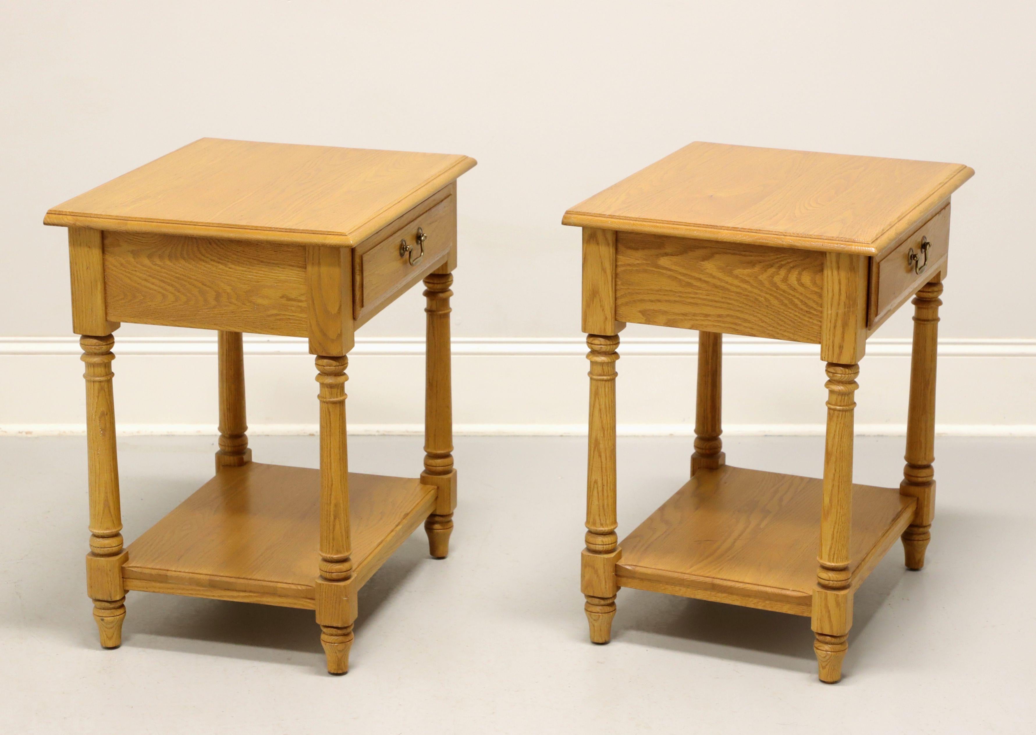 A pair of American Colonial style nightstands, unbranded, similar in quality to Thomasville. White oak with bass hardware, ogee edge to the top, turned side posts, undertier shelf and spade feet. Features one drawer of dovetail construction. Likely