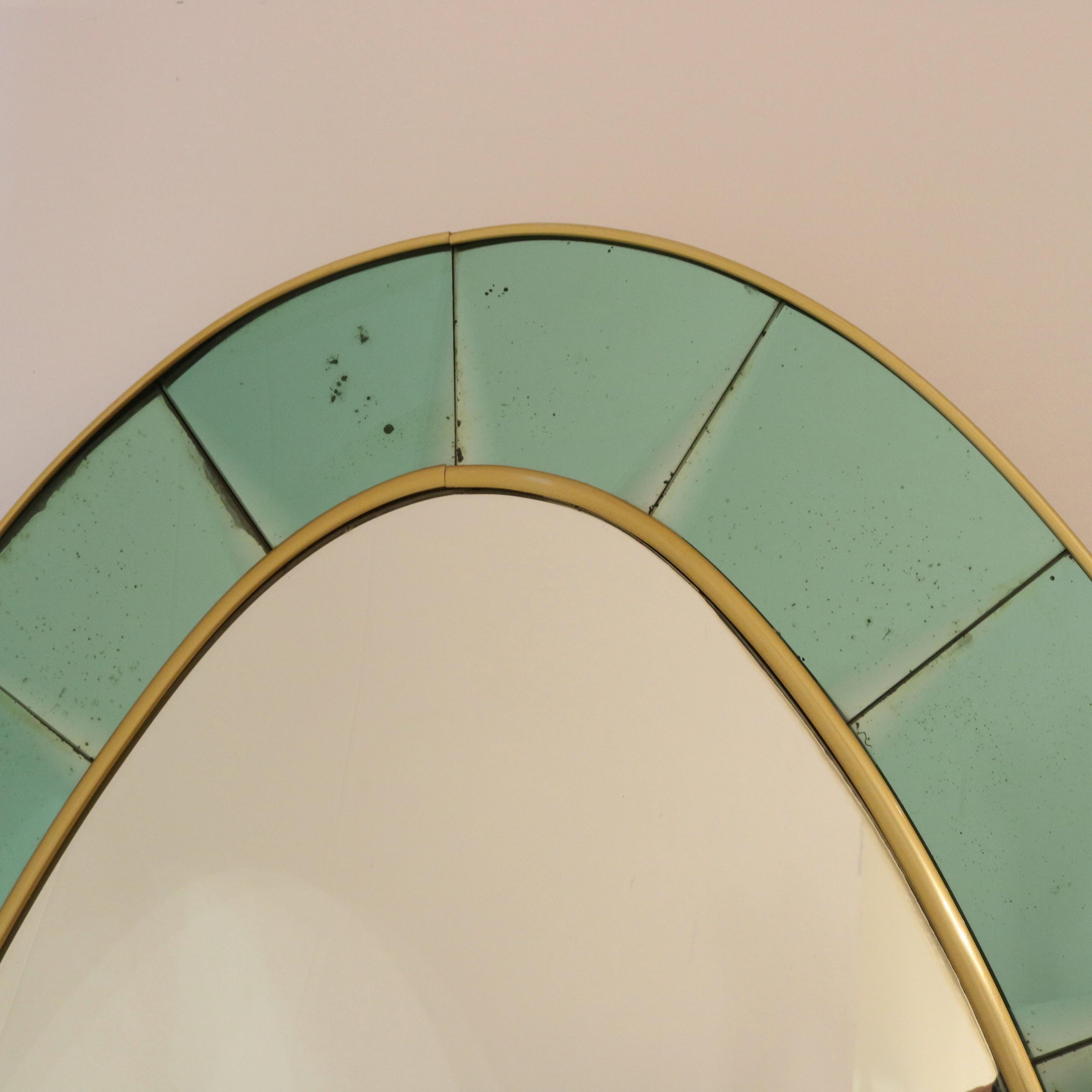 Cristal Arte large scale oval floor mirror model #2690. A frame of beveled, colored, crystal glass is outlined by brass filet.  A thick clear polished glass shelf is mounted in the lower third of the mirror. It rests on a stylized scrolled brass