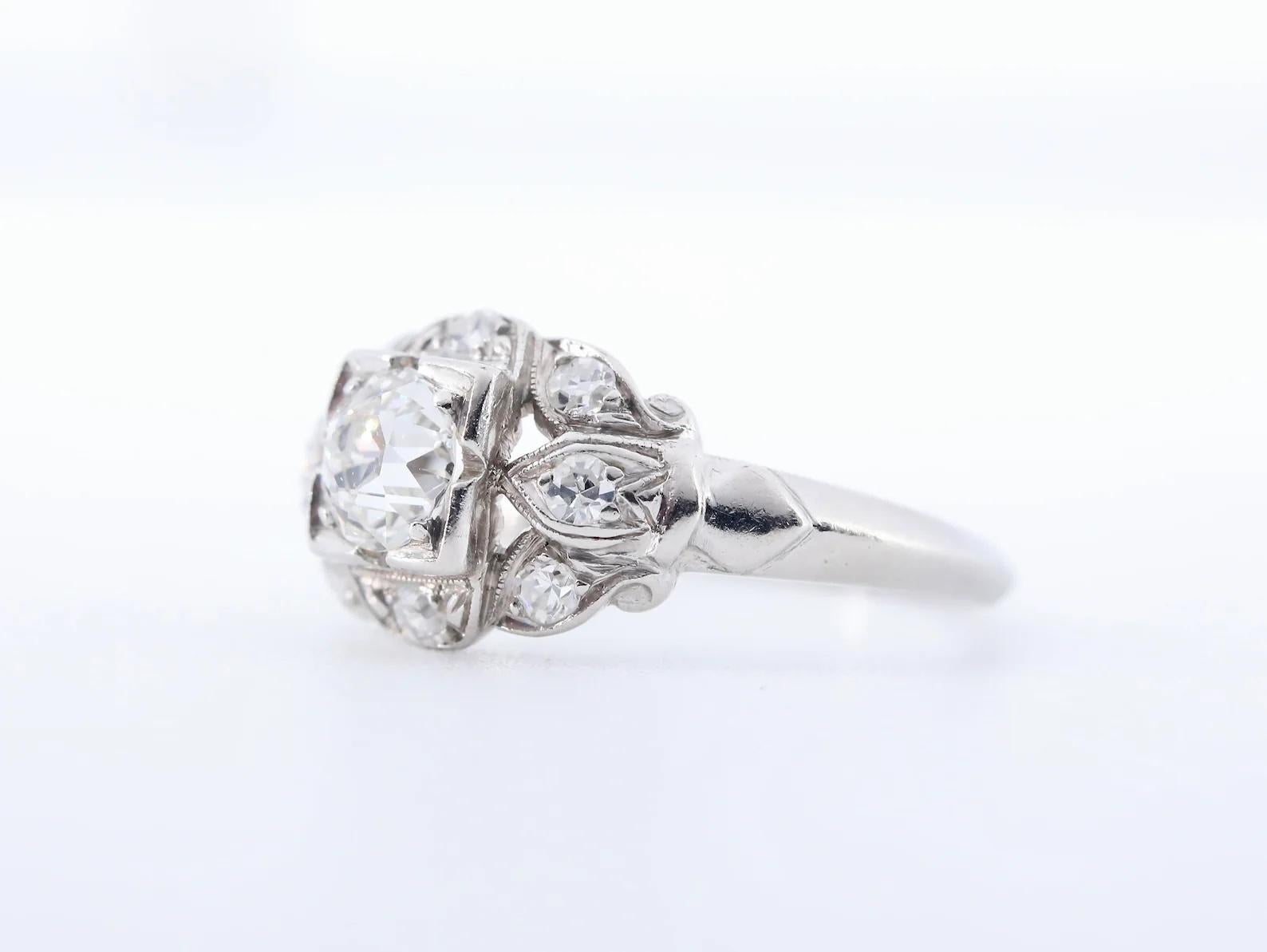 A handmade late Art Deco period diamond engagement ring in platinum.

Centered by a 0.60 carat old mine cut diamond, and framed by an additional eight pave set diamonds of 0.16ctw.

The diamonds all of G/H color, and VS clarity.

Hallmarked, and