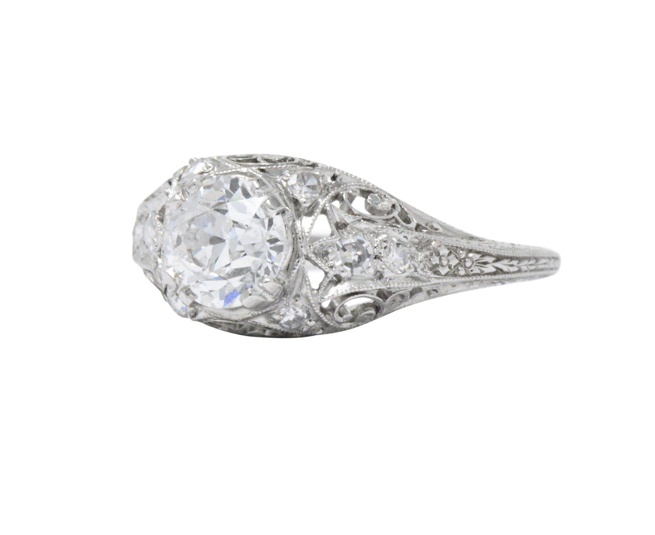 Gorgeous late Art Deco platinum engagement ring centering a 1.01 carat old European cut diamond, E in color and VS2 in clarity

Mount decorated with swirl and floral design accented with .20 carat total weight of single cut diamonds

Top measures