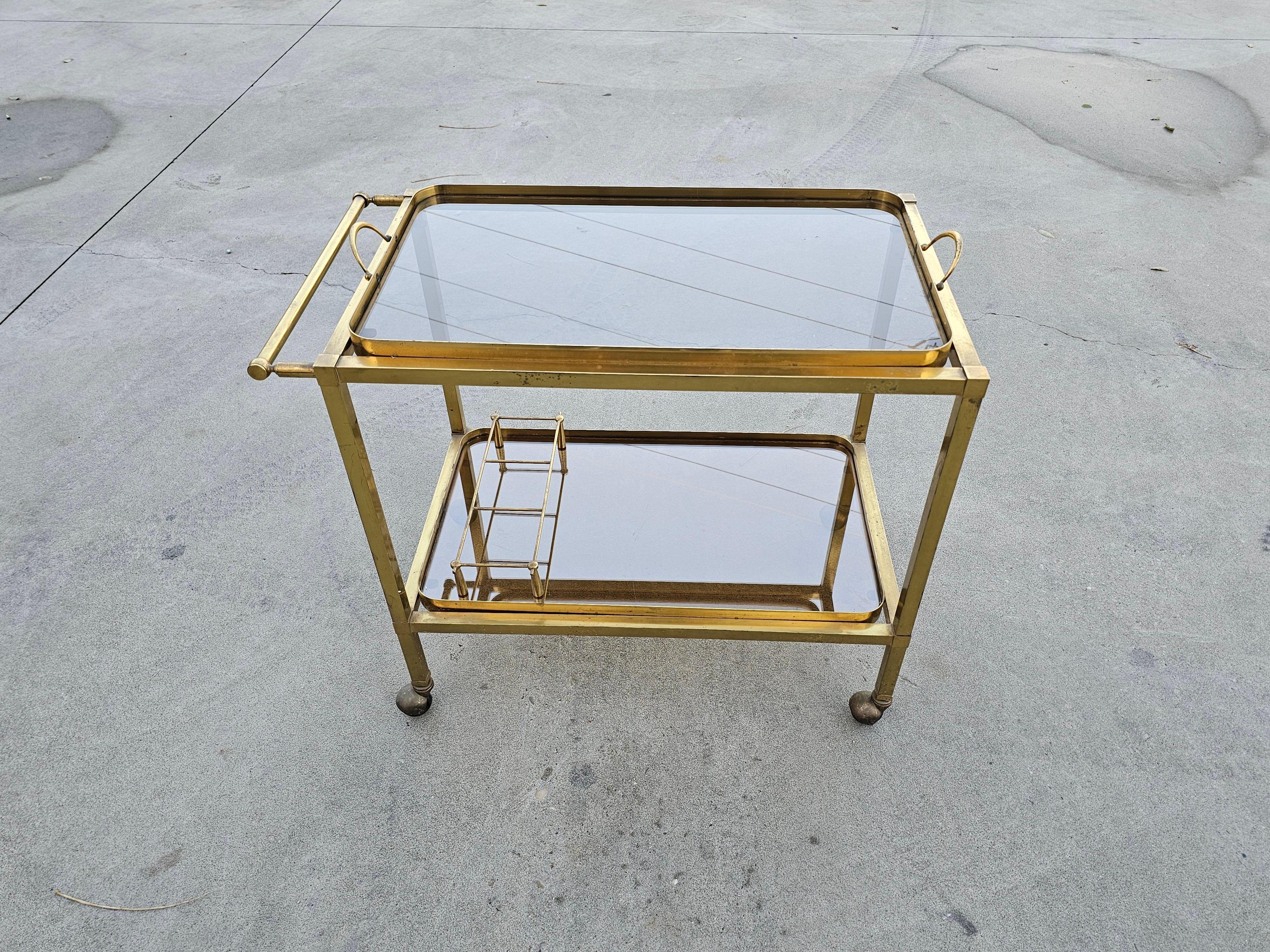 In this listing you will find a gorgeous and luxurious late Art Deco 2-Tier Bar Cart done in gilt bronze, with smoked glass tops. The top tier can be taken off and used as a serving tray, as seen in one of the pictures. Attr. to Maison Bagués. Made
