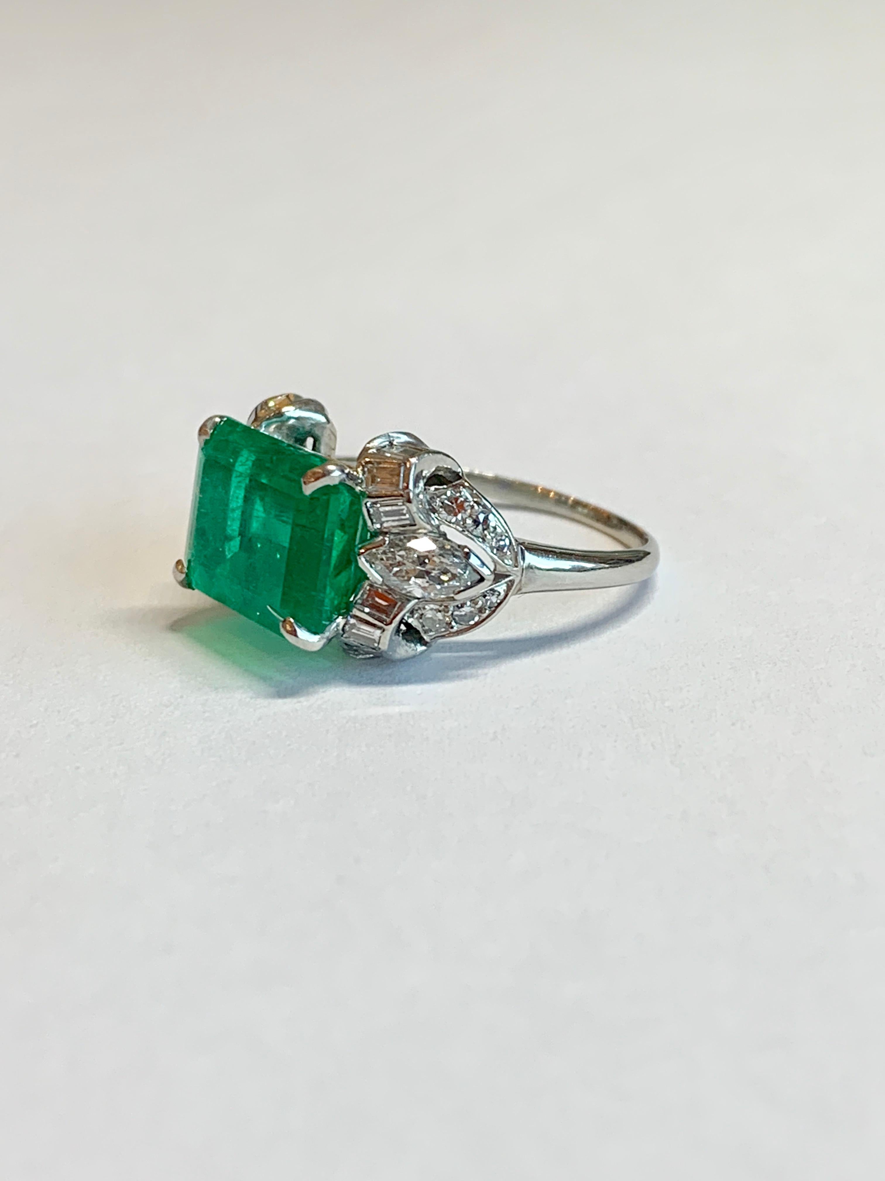 This dazzling Late Art Deco ring circa 1935 highlights an east-west set emerald weighing exactly 4.97 carats with an accompanying GIA certificate #2183240642 stating the stone is a natural emerald with Colombian origin. The platinum mounting is