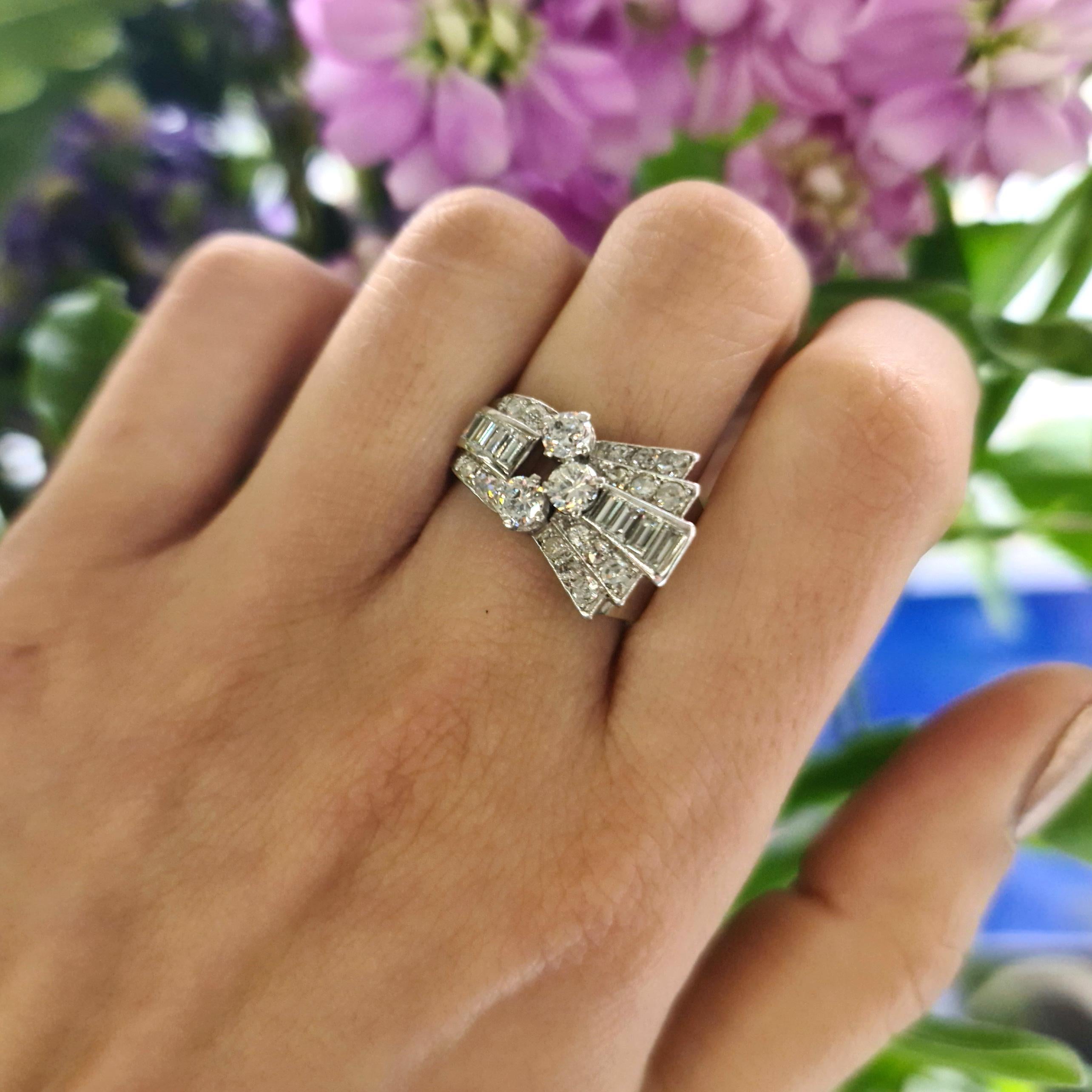 An Art Deco, Odeonesque style, diamond cocktail ring, with three, claw set, round old-cut diamonds, on a baguette and eight-cut diamond set stepped fan, mounted in platinum, with an estimated total diamond weight of 1.60ct, circa 1940.