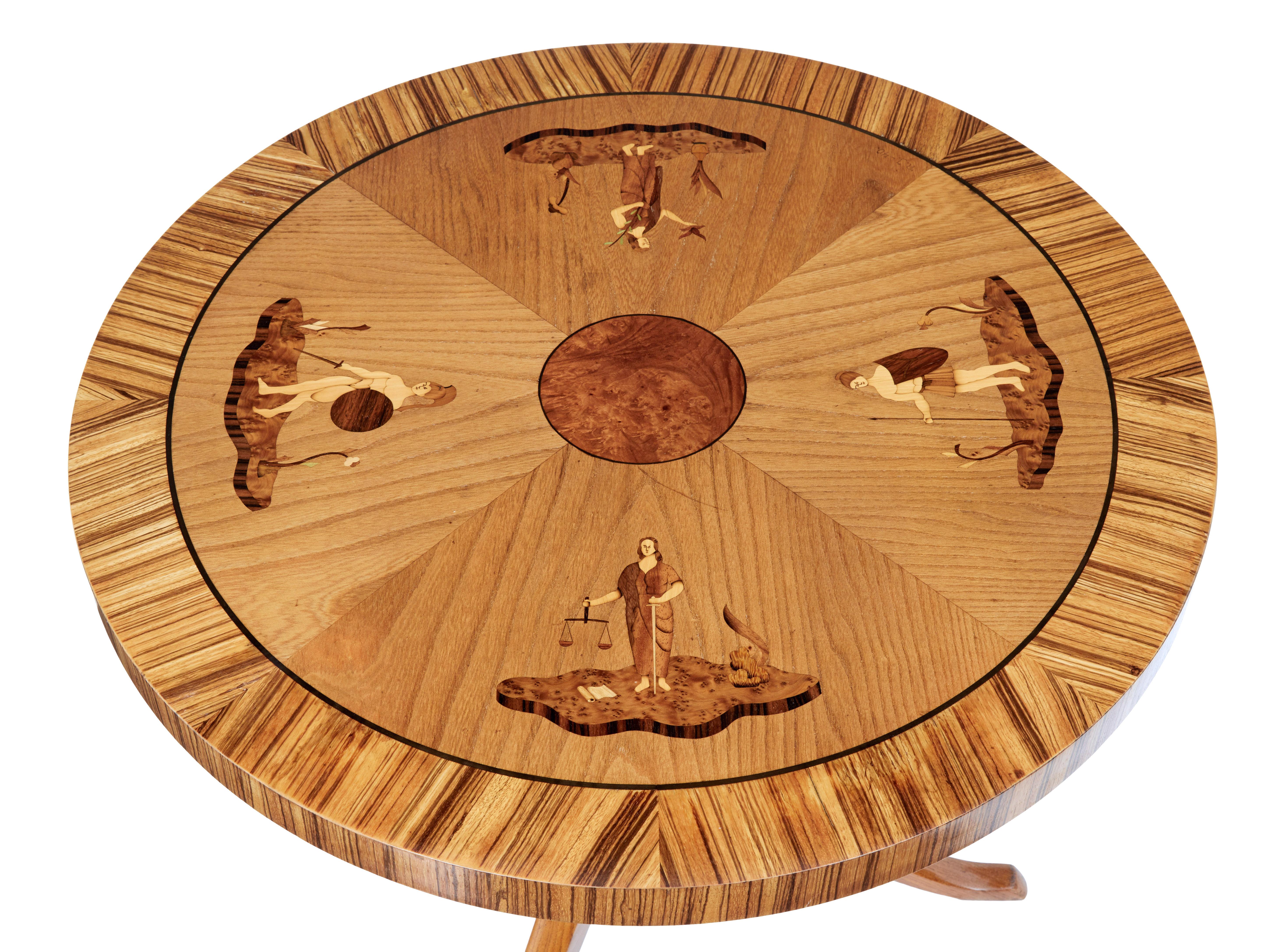 Late Art Deco Scandinavian coffee table, circa 1940.

Circular top, round burr center surrounded by 4 mythical women on each quarter. Inlaid with walnut, rosewood and pear wood. Signed n.J with the date of '40.

Standing on an elm stem, 3 legs