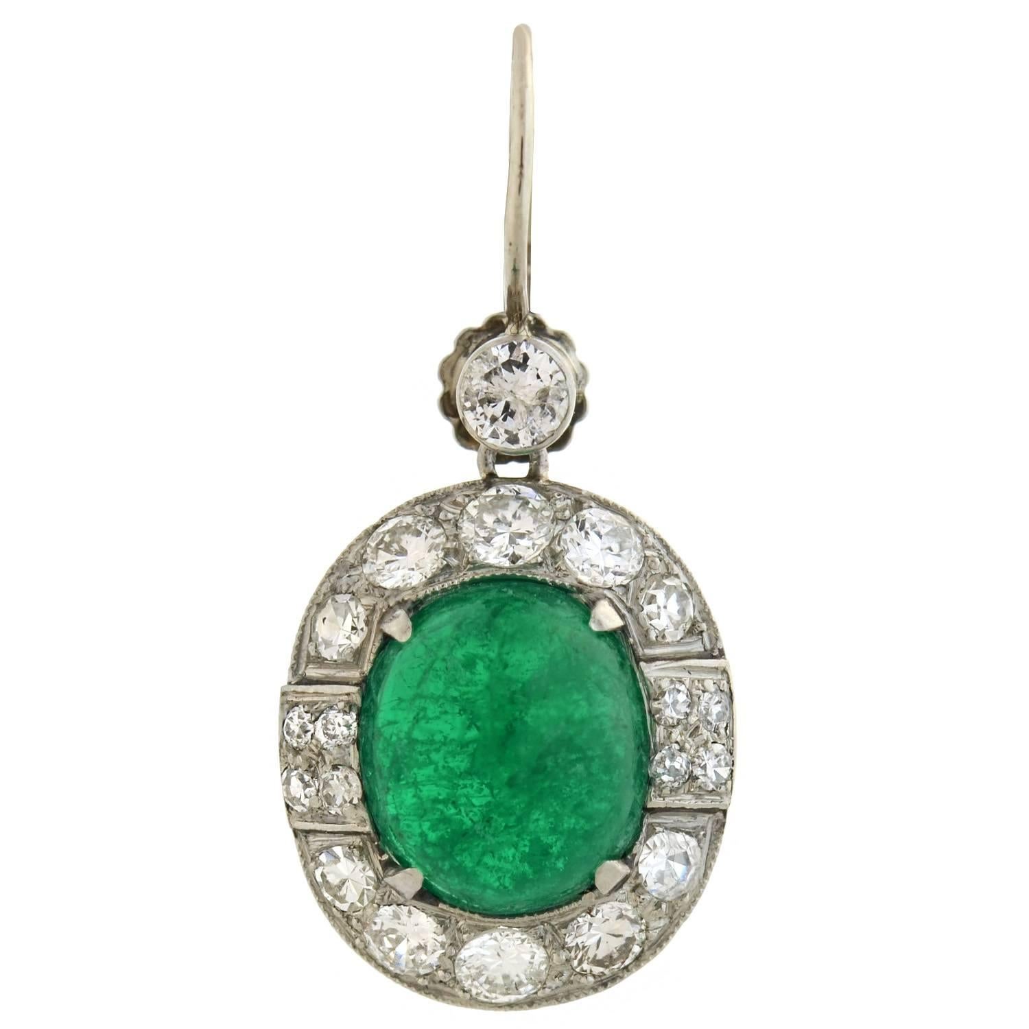 A spectacular pair of emerald and diamond earrings from the late Art Deco (ca1930s) era! These breathtaking earrings are crafted in 18kt white gold and hang from 14kt white gold wires. Each earring frames a luscious emerald cabochon at the center of