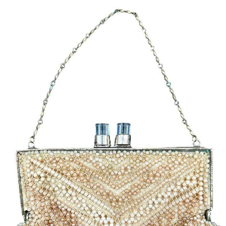 Late 1940s Art Deco beaded white purse/clutch. This stylish purse features a silvertone & lucite clasp complemented by a stylish chain handle with a beaded bag attached. The interior is lined with luxurious white silk, adding to its refined