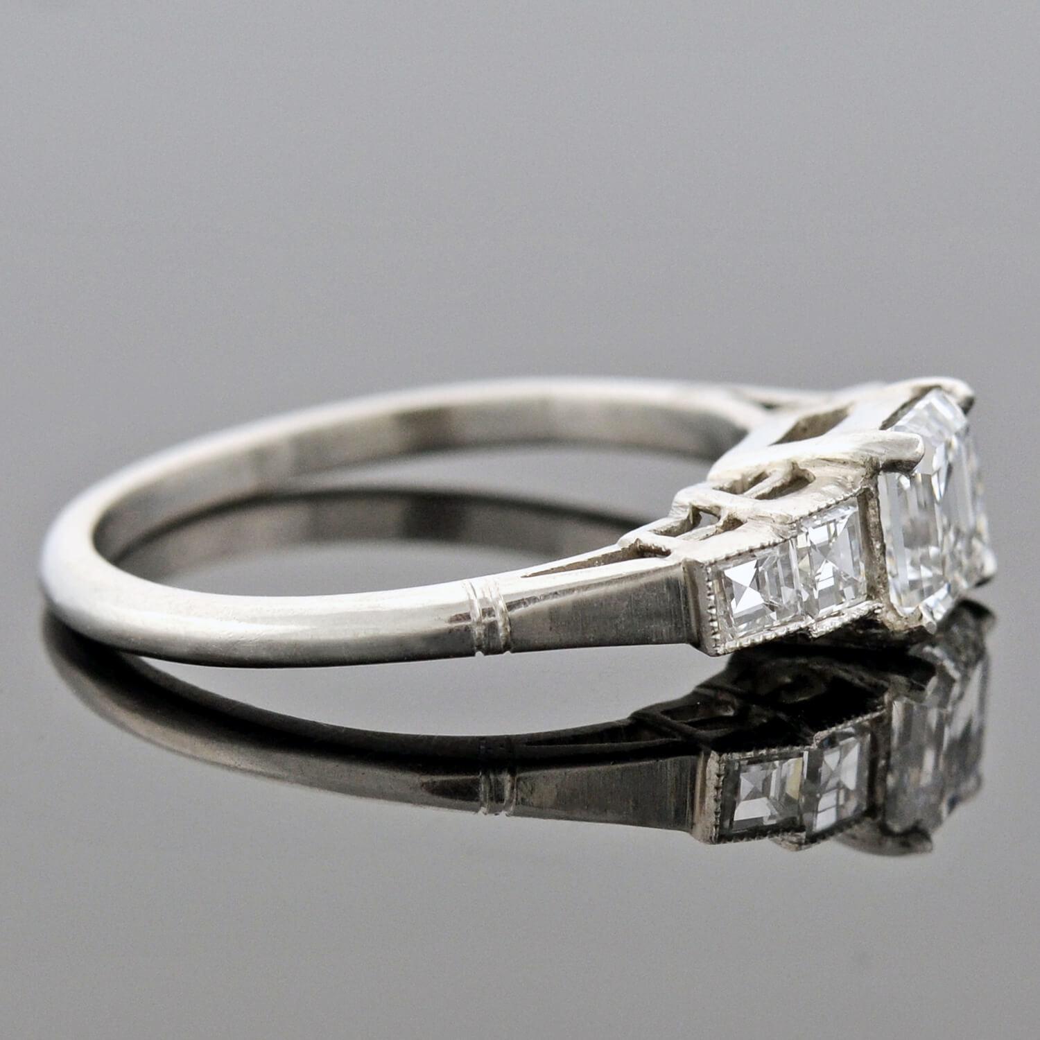 A stunning diamond engagement ring from the late Art Deco (ca1930s) era! This gorgeous platinum ring frames a 1.03ct Asscher Cut (also known as a Square Emerald Cut) diamond at the center. The stone is held within a 4-prong setting, and is graded