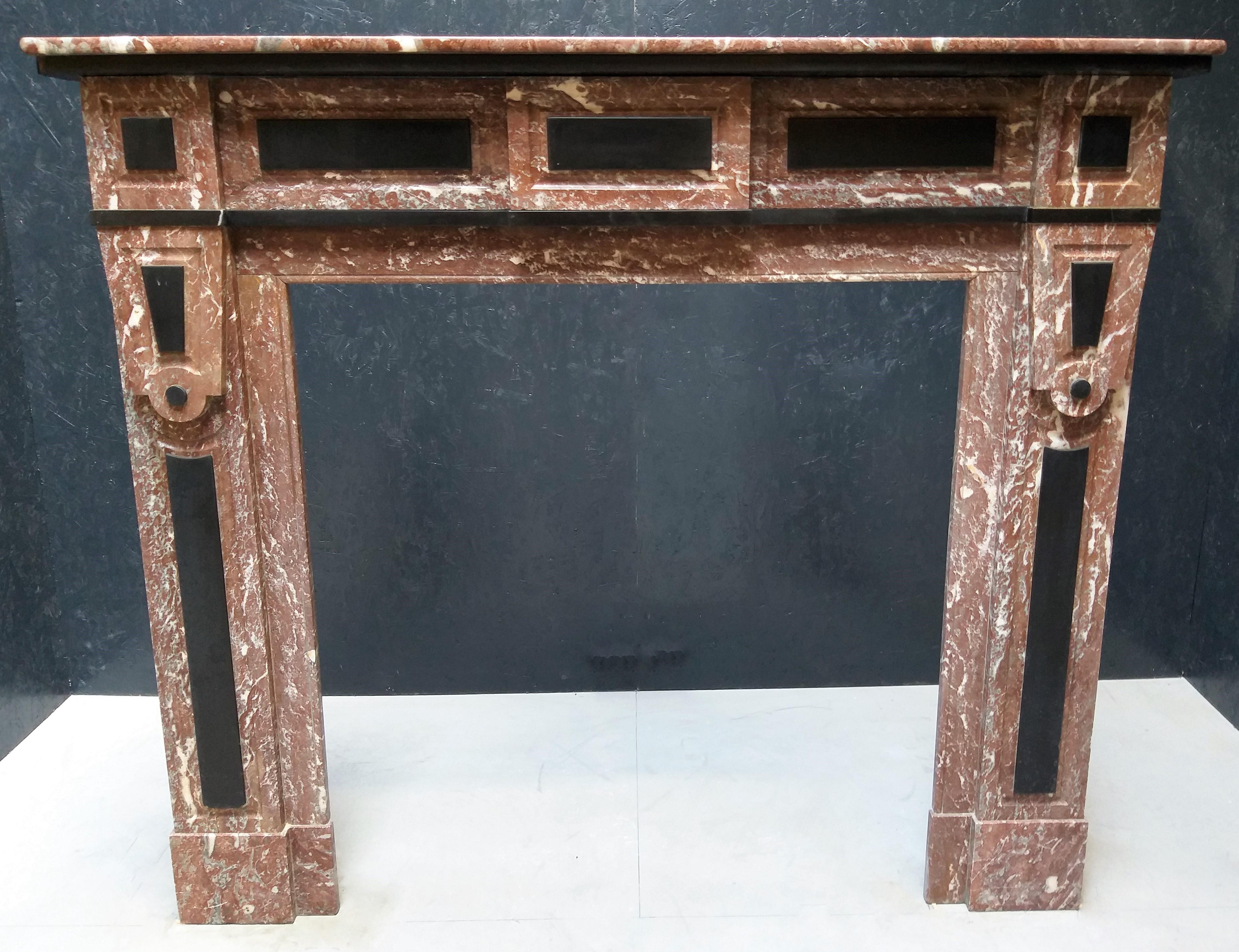 This fireplace in late Art Deco - style was made in the late 19th century in Belgium, where you could find also the used marbles: Rouge Royal and Noir de Mazy. The combination of these two marbles gives a vivid movement to this fireplace.  It has a