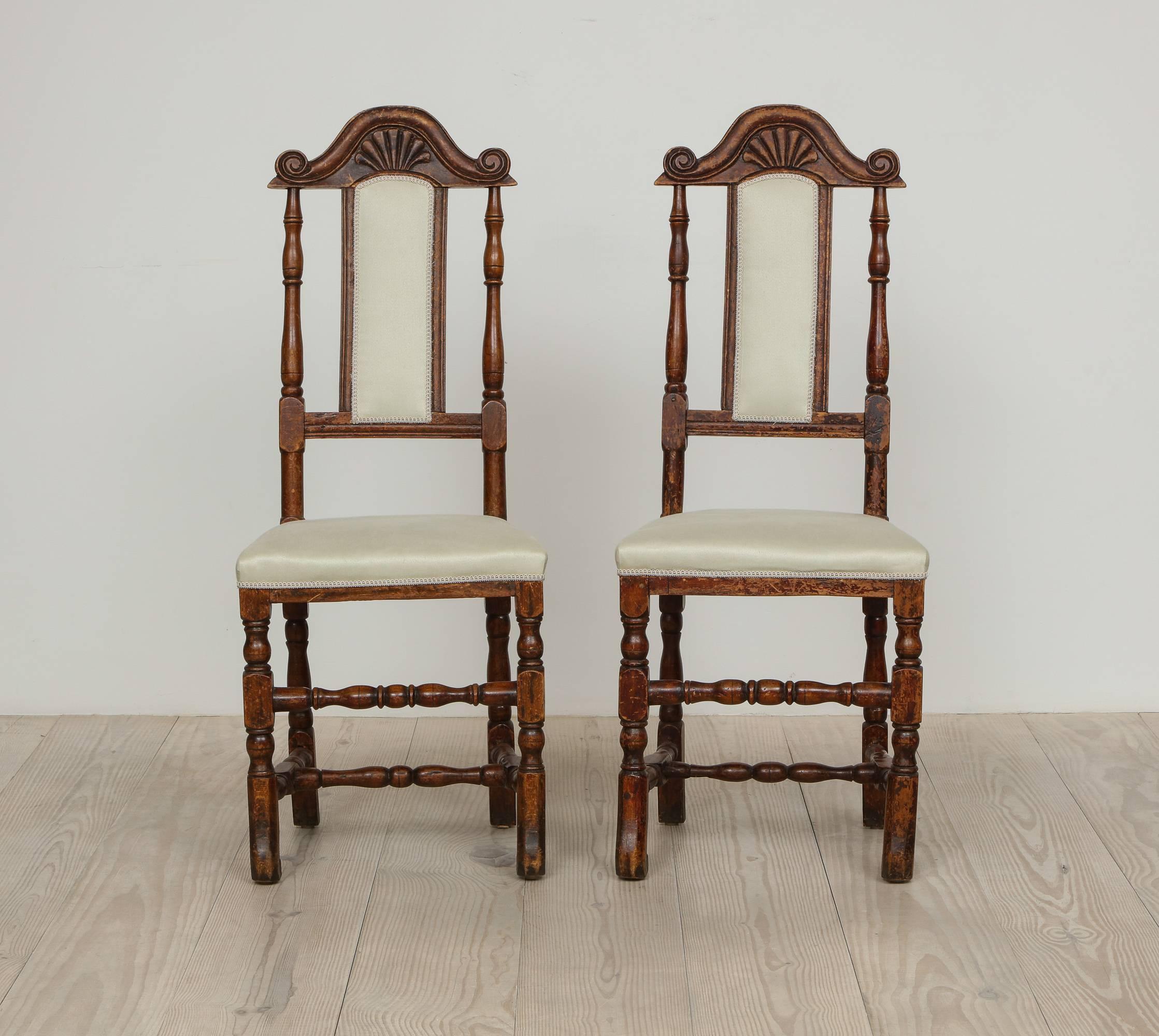 A pair of late Baroque Swedish chairs, origin: Sweden, circa 1750 -1760, reupholstered in linen sateen fabric from Rogers & Goffigon, the wood stained to resemble walnut.  

The form of these chairs, including their narrow back splat surmounted by a
