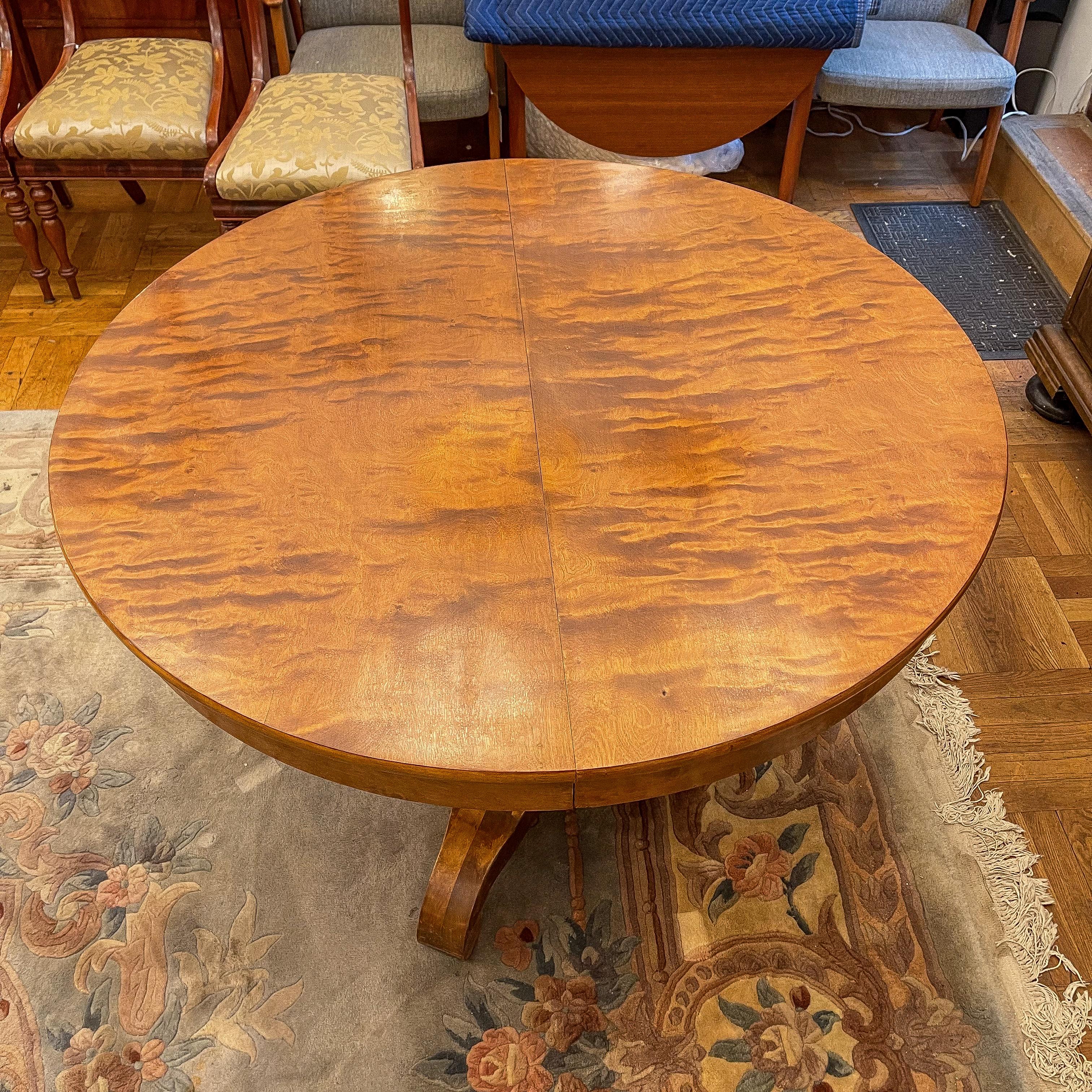 An elegant dining table from the end of the 19th century that extends easily for additional guests. All facing surfaces are veneered in birch, stained to a rich caramel color.  The entire assembly rests on an elegant pedestal base.  With one leaf,