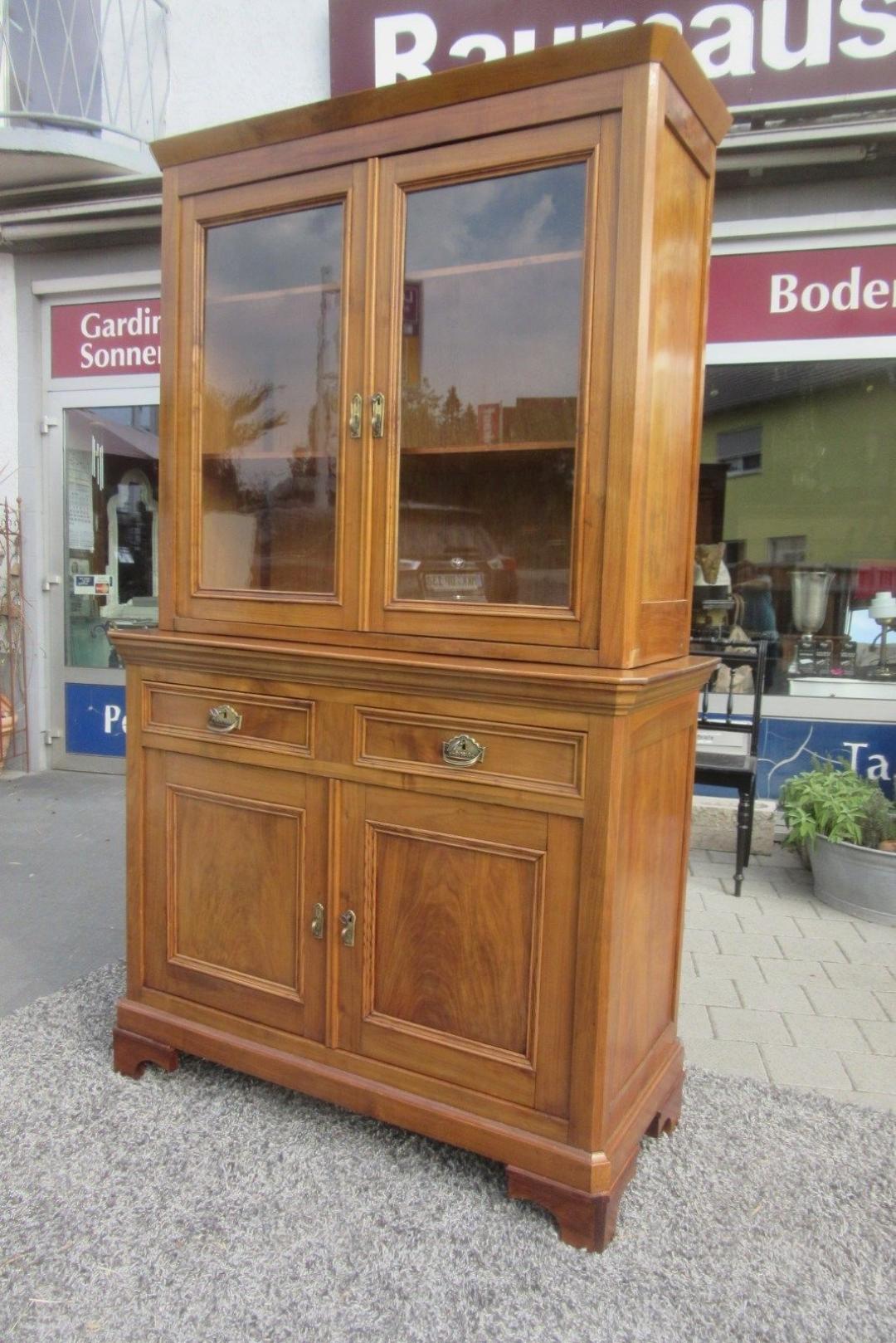 Elegant late Biedermeier kitchen cabinet or vitrine cabinet made of dark veneered cherrywood. Features two doors, two drawers and a vitrine compartment with two shelves. Comes with original keys and locks. The body is made of massive cherrywood. In