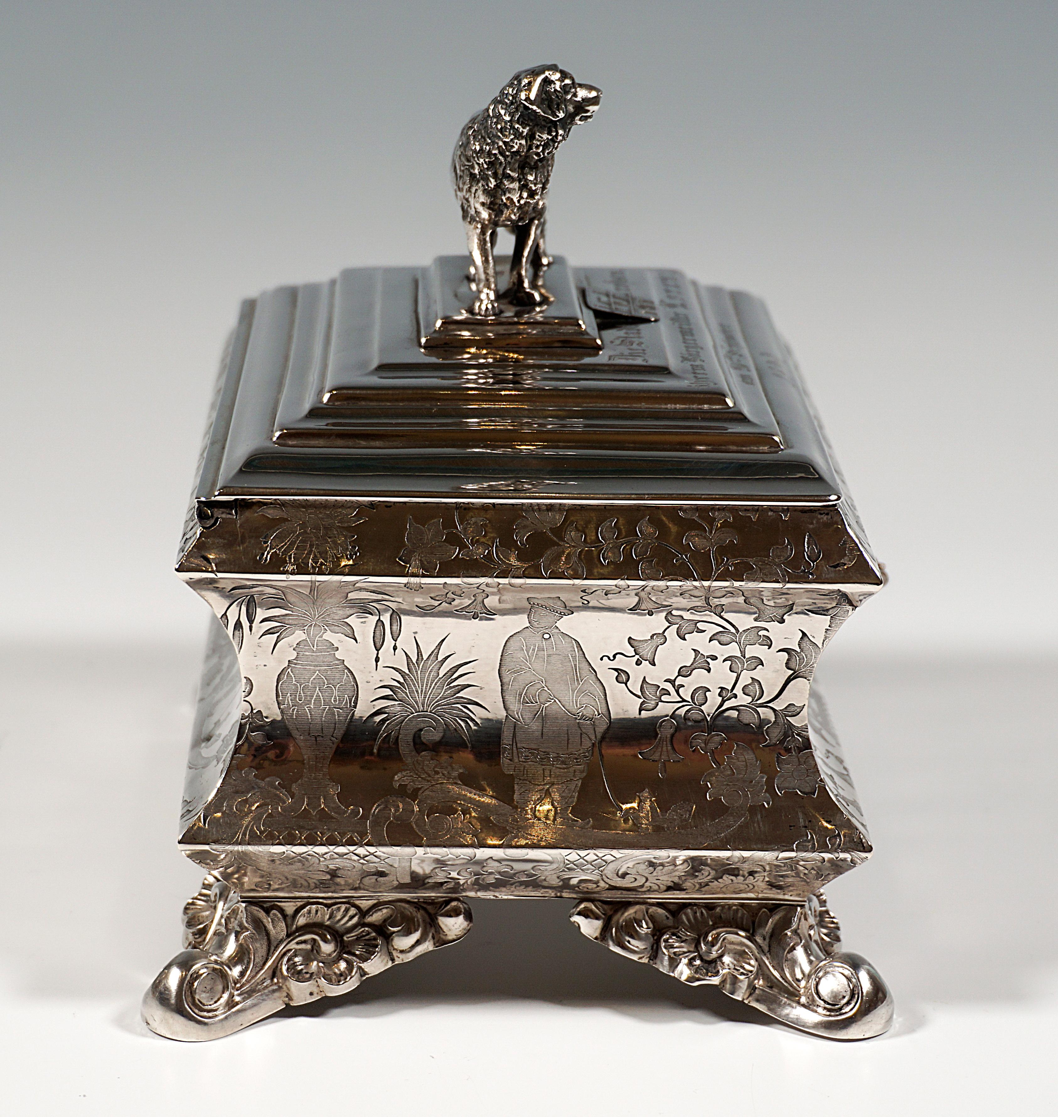 Large late Biedermeier silver sugar box on four voluted, leaf-decorated feet, merging into a rectangular body with wide fluting in the middle, walls decorated with fine chinoiserie decoration, stepped hinged lid, crowned by a fully sculpted