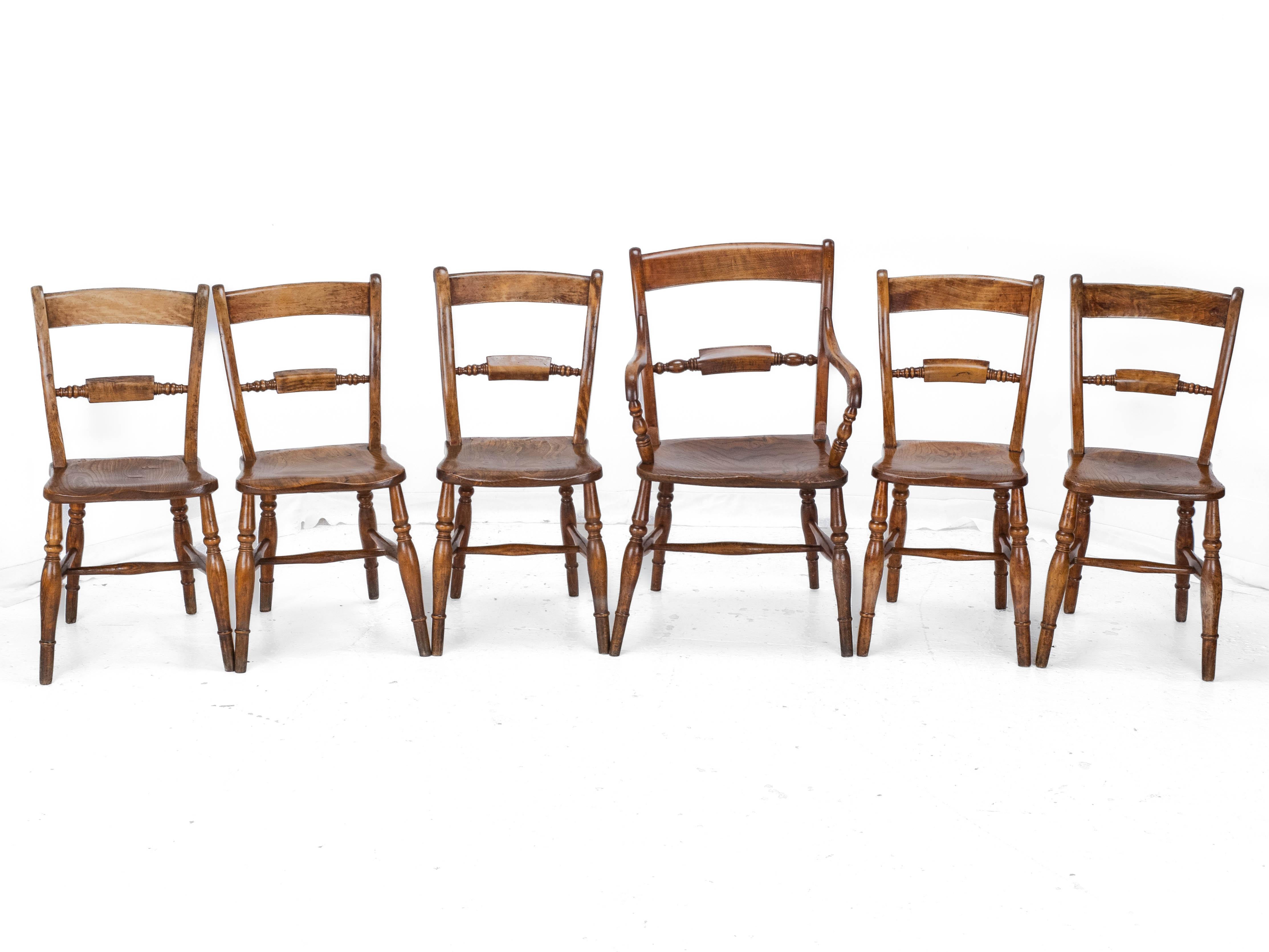 Un set di 6 sedie da pranzo Windsor provinciali in olmo, frassino e faggio con intagliatore, risalenti alla fine del XIX secolo. Composto da 5 sedie e da un singolo intagliatore, questo set è caratterizzato da legni massicci e ben lavorati e da un