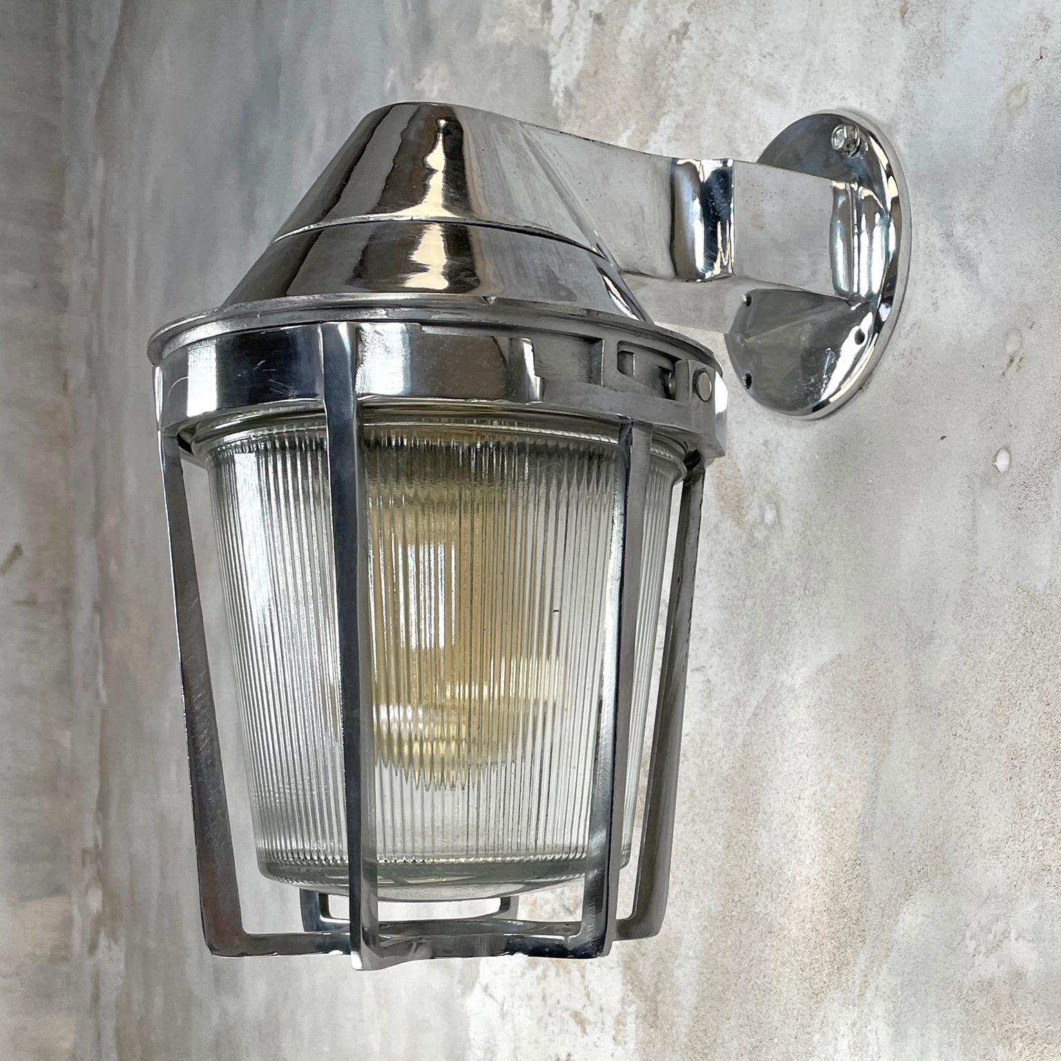 A large vintage cast aluminum sconce with prismatic glass shade and cage. These aluminum wall light fixtures are made by Appleton Electric USA with outstanding build quality and materials. The main body is cast aluminum, the cage mechanically