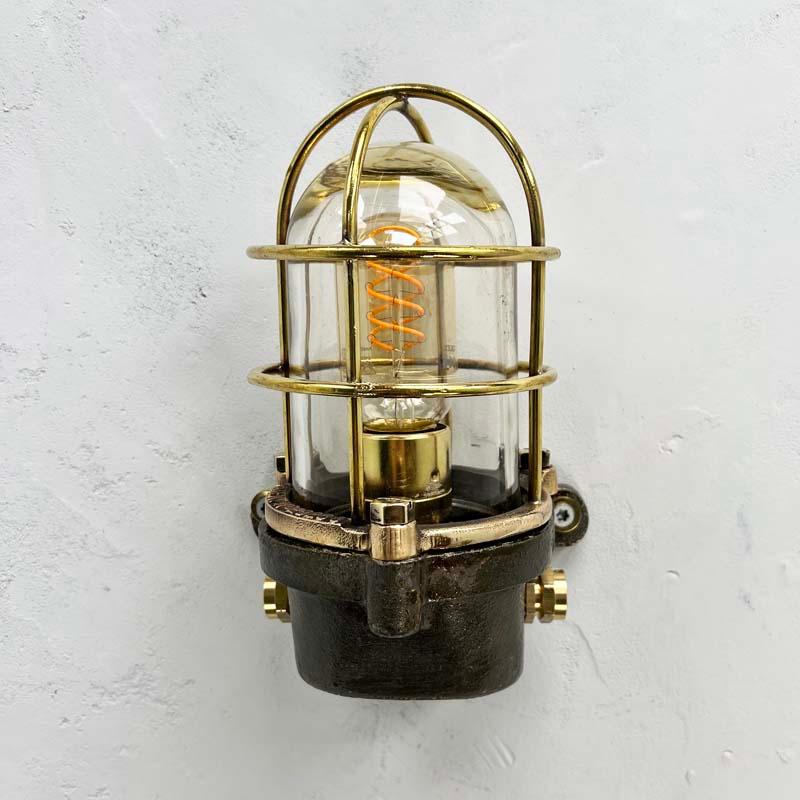 British made vintage industrial cast steel wall light fixture with brass and bronze cage and glass dome. 

Professionally restored and rewired by hand in our workshop, these robust wall lights have been reclaimed from cargo ships where they would