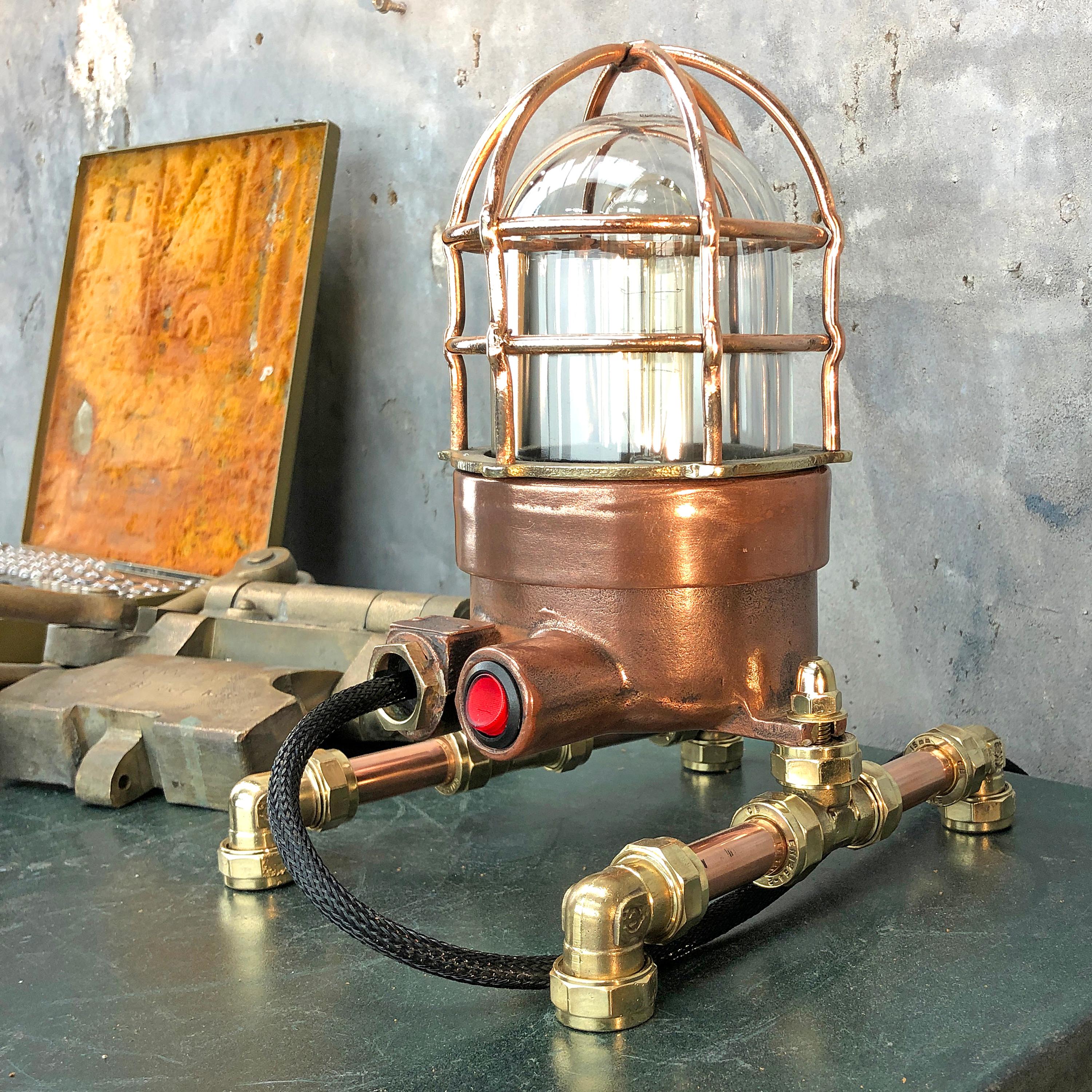 1970s explosion proof passage way light reclaimed from a super tanker modified to function as a table or desk lamp.

The light itself is made from copper and brass and has a tempered glass dome and protective cage.

These lights were