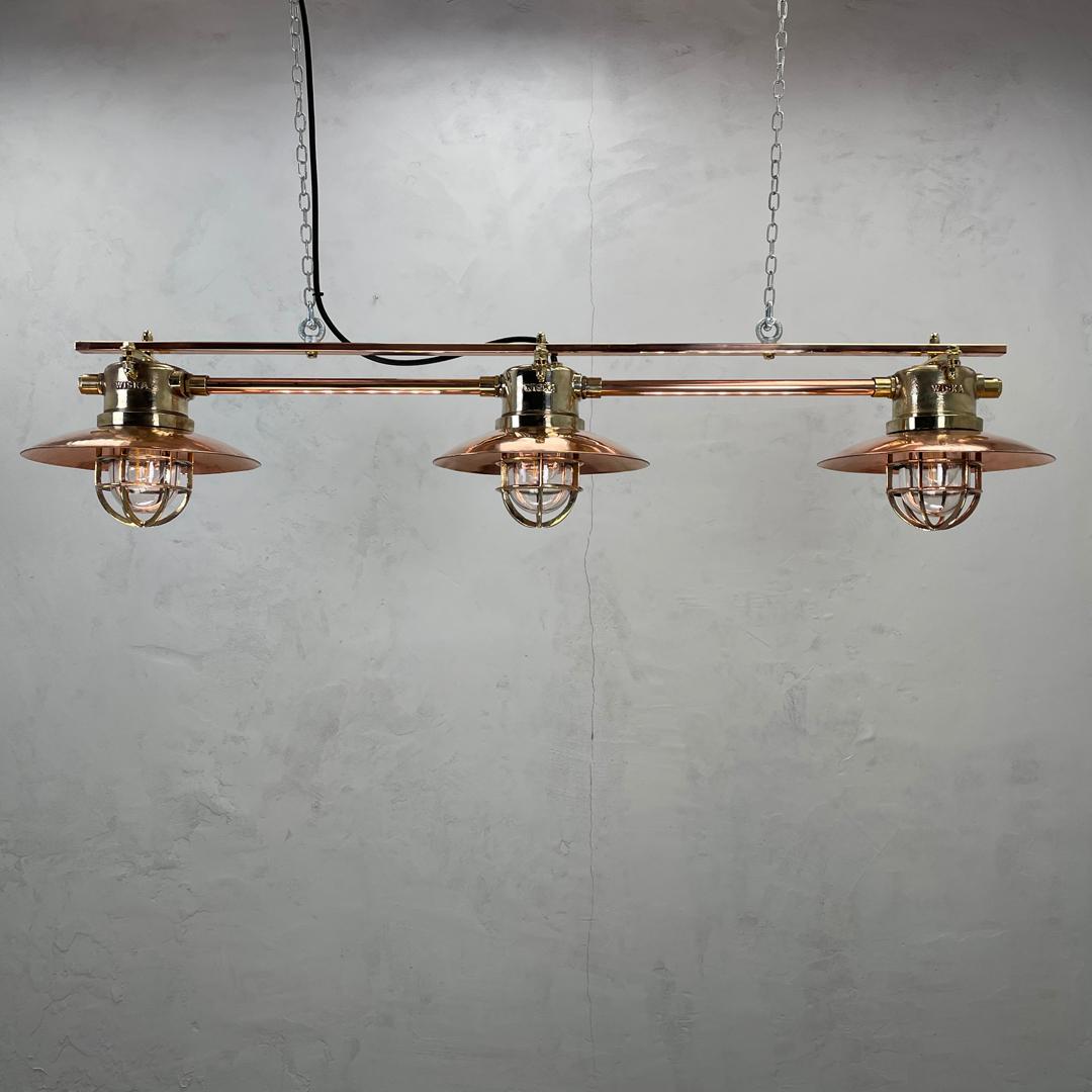A copper and brass 3 lamp bar comprising of 3 cast brass explosion proof pendants made in the 1970's by Wiska of Germany who are a manufacturer of marine grade fixtures and fittings.

At Loomlight we have created a 3 lamp arrangement using solid