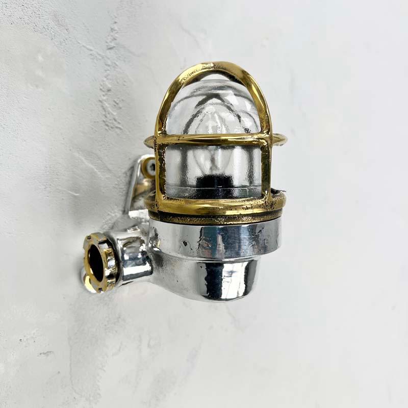 A Small Japanese industrial aluminium and brass cage wall light with glass dome and protective cage.

The main body is made from cast aluminium which features a screw in glass dome and cast brass protective cage.

These are polished to a bright