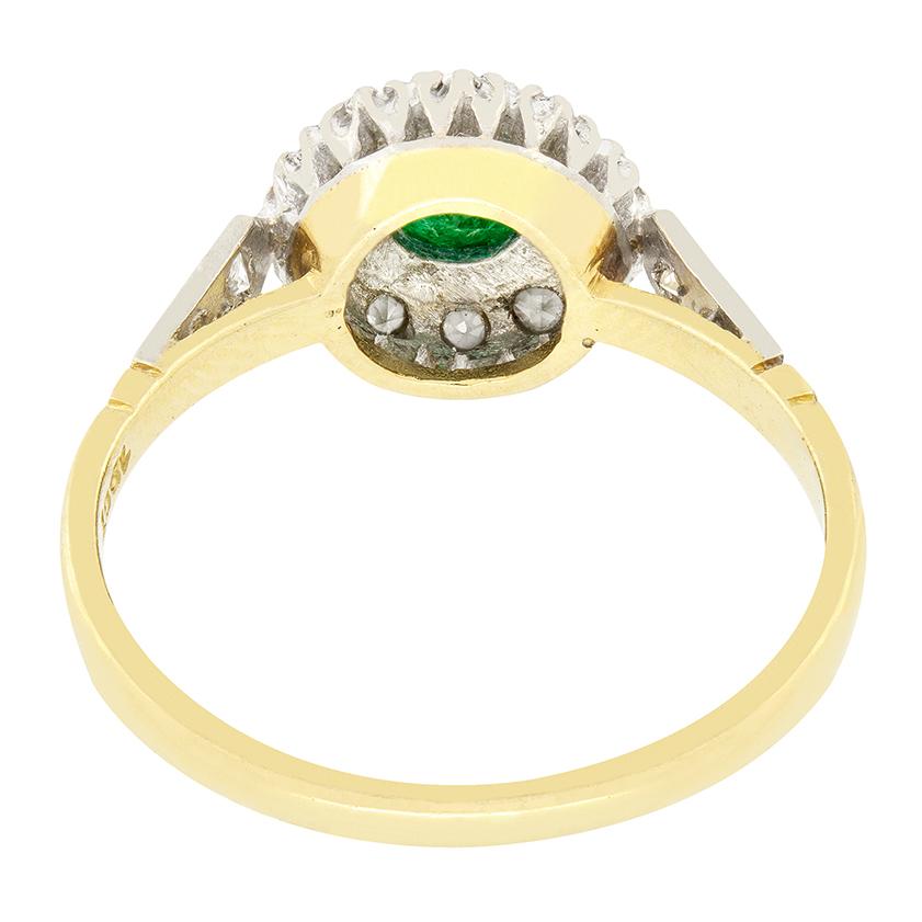 A bright green 0.60 carat emerald is set in the centre of this Late Deco cluster ring. The round cut emerald stands out beautifully in amongst the cluster of 10 eight cut diamonds surrounding, with an additional two down each shoulder. The diamonds