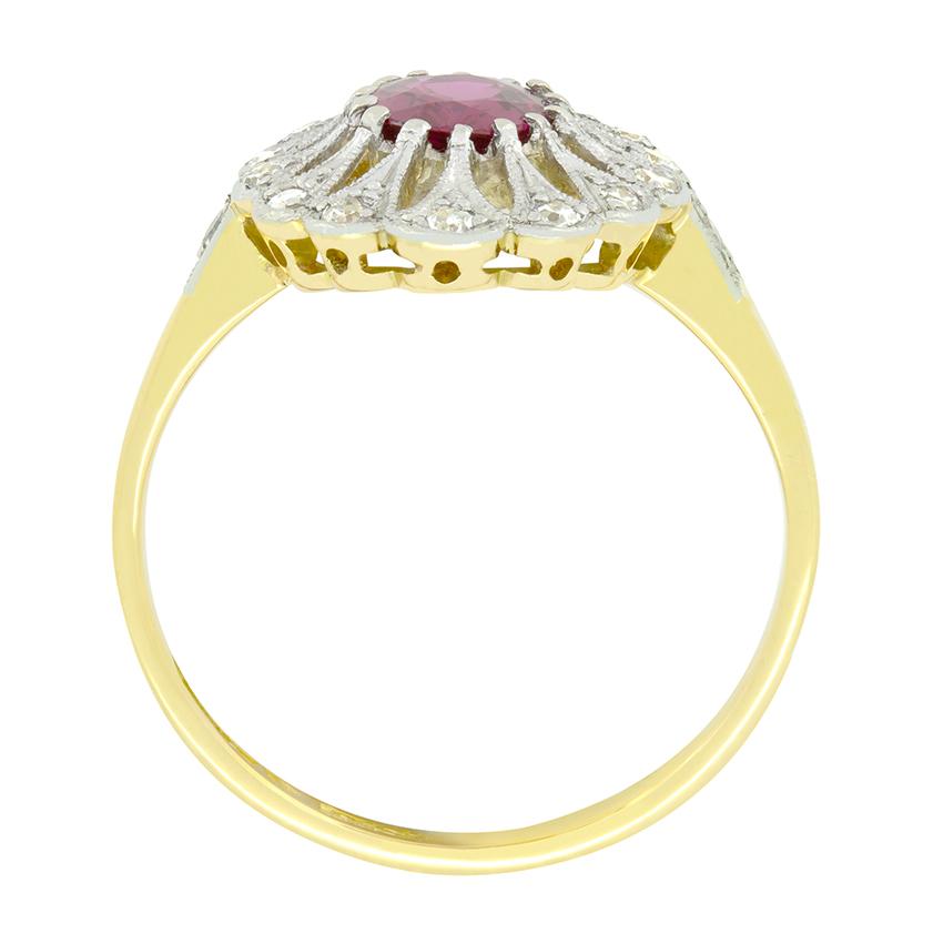 Questo elaborato anello a grappolo degli anni '30 è incentrato su un rubino ovale da 0,60 carati. Incastonato nel platino, il vibrante rubino è circondato da un'intricata lavorazione del metallo che presenta altri quattordici diamanti taglio