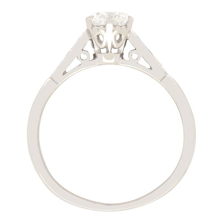Dieser zeitlose Verlobungsring im späten Deco-Stil besteht aus einem 0,65-Karat-Diamanten, der durch diamantbesetzte Schultern hervorgehoben wird. Der runde Diamant im Brillantschliff hat eine Farbe von G und eine Reinheit von SI1 und fängt das
