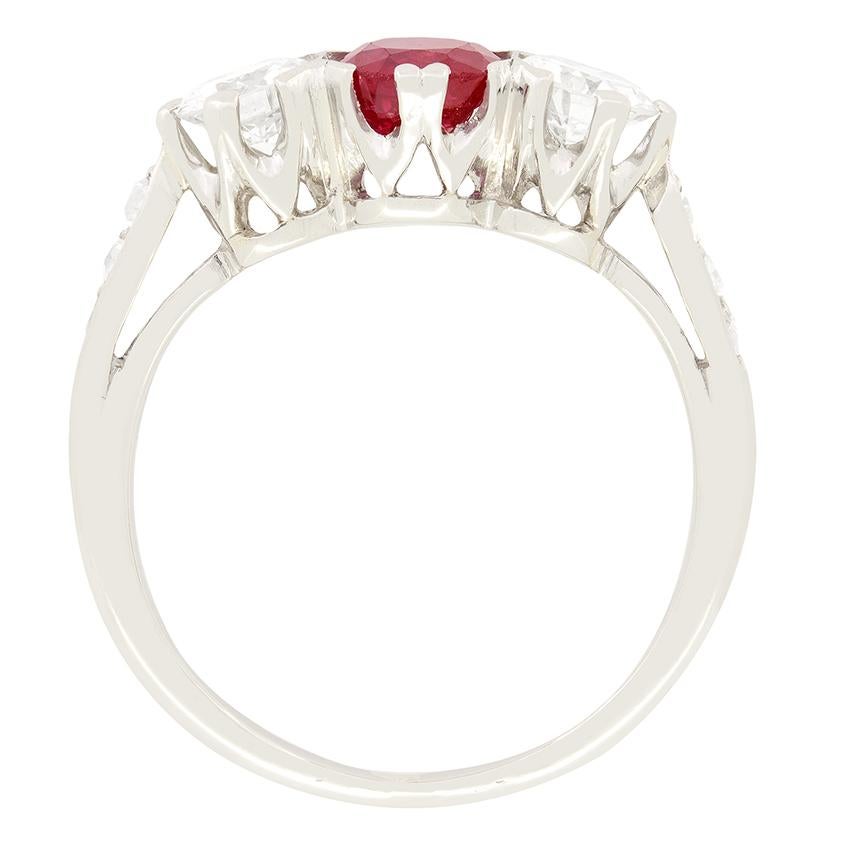 A luscious red ruby is flanked by transitional cut diamonds in this three stone ring from the 1940s. The ruby is an oval cut stone weighing 0.80 carat. The transitional cut diamonds set to either side total to 0.60 carat and are of good quality,