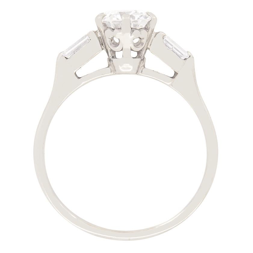 A timeless and elegant solitaire engagement ring set with one round brilliant cut diamond set in a six claw platinum collet. The diamond has been estimated as F in colour and VS2 in clarity. Set to either shoulder is a baguette diamond, weighing