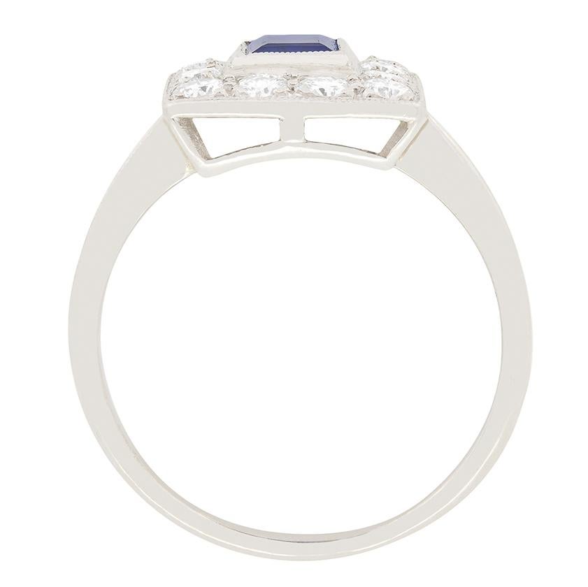 Set to centre of this splendid platinum Late Deco ring is a vivid blue, baguette cut sapphire with a weight of 0.90 carat. Highlighting the beautiful blue tones of the sapphire is a halo of transitional cut diamonds surrounding, totalling to 0.70