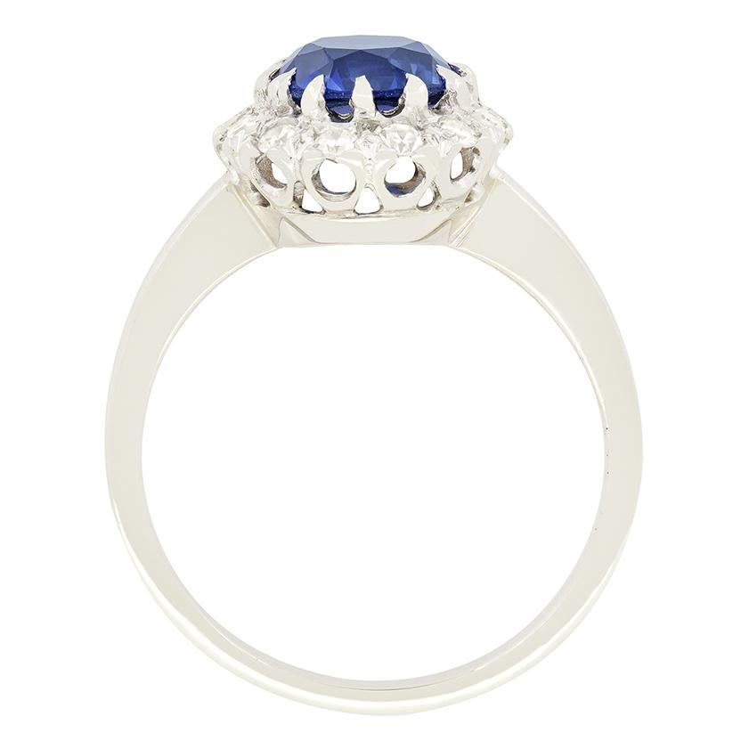 Risalente agli anni '40, questo splendido anello a raggiera in stile Late Deco ha come cuore un vibrante zaffiro blu naturale. La pietra a taglio rotondo pesa 1,70 carati e non è riscaldata. L'aureola circostante è composta da 0,24 carati di