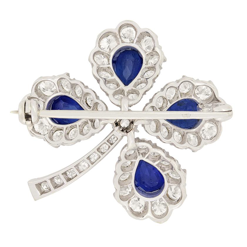 This platinum Late Deco flower brooch features four, deep blue, pear cut sapphires claw-set to create the petals of the flower. Each of the sapphires weigh 0.50 carat and are completely natural.  A single transitional cut diamond adorns the centre,