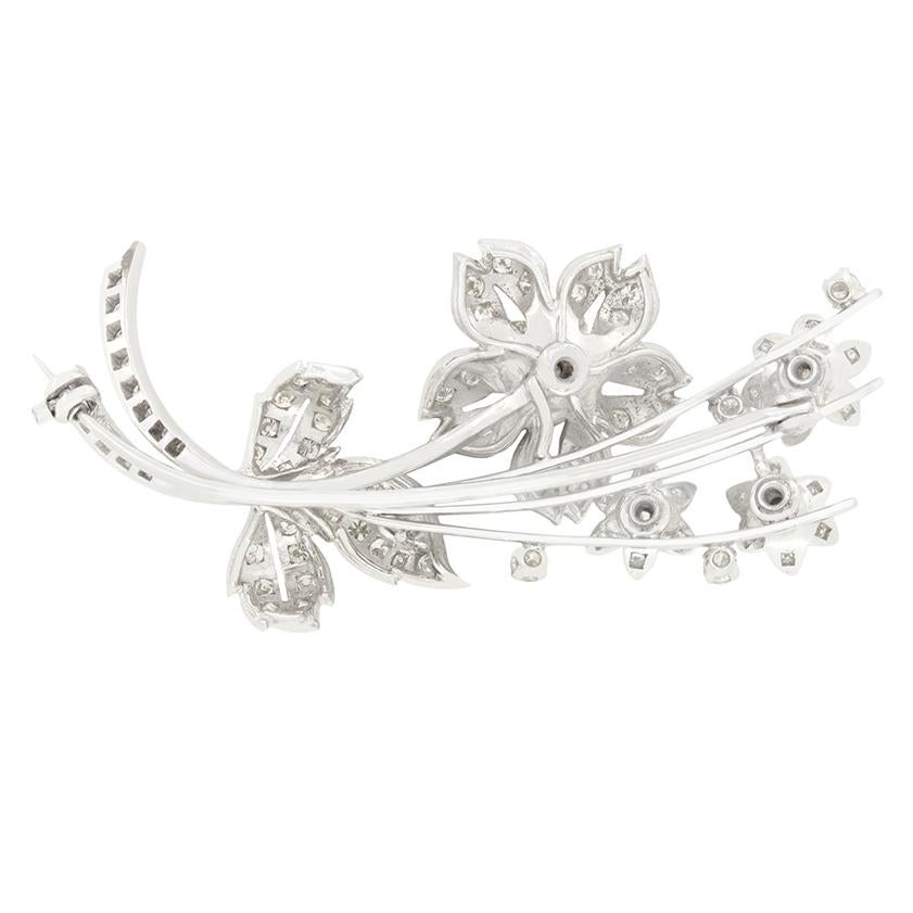 Questa spilla di fine Art Déco mostra una bellissima composizione floreale realizzata interamente in platino. Al centro si trova un diamante tondo brillante da 0,25 carati, circondato da delicate formazioni a petalo con pietre tonde brillanti più