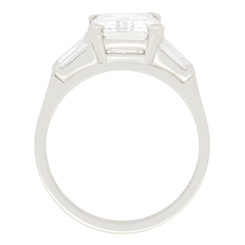 Un magnifique diamant taille émeraude de 3,18 carats se détache distinctement de ses quatre griffes. Il a été classé par EDR comme étant de couleur I et de pureté VVS2. De part et d'autre, une paire de diamants baguettes effilés, d'un poids de 0,05