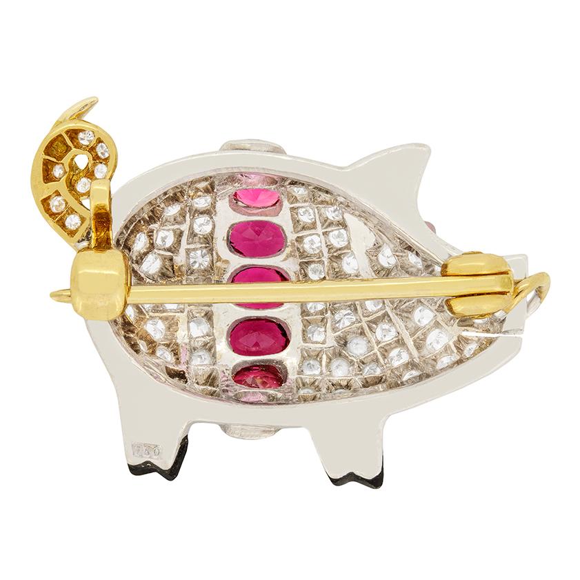 A sweet piglet brooch dating back to 1940s, the Late Deco era. The piglets body is made up of 1.00 carat of grain set diamonds with seven pink sapphires going around its body. The vivid pink sapphires total to 0.54 carat and are oval in shape. There