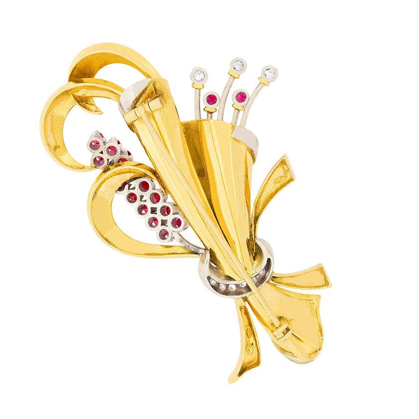 This original 1940s brooch, with box, is a beautifully made design with a collection of diamonds and rubies. The hand crafted brooch is a floral design made in both 18 carat yellow gold and platinum. There is a collection of 8-cut diamonds