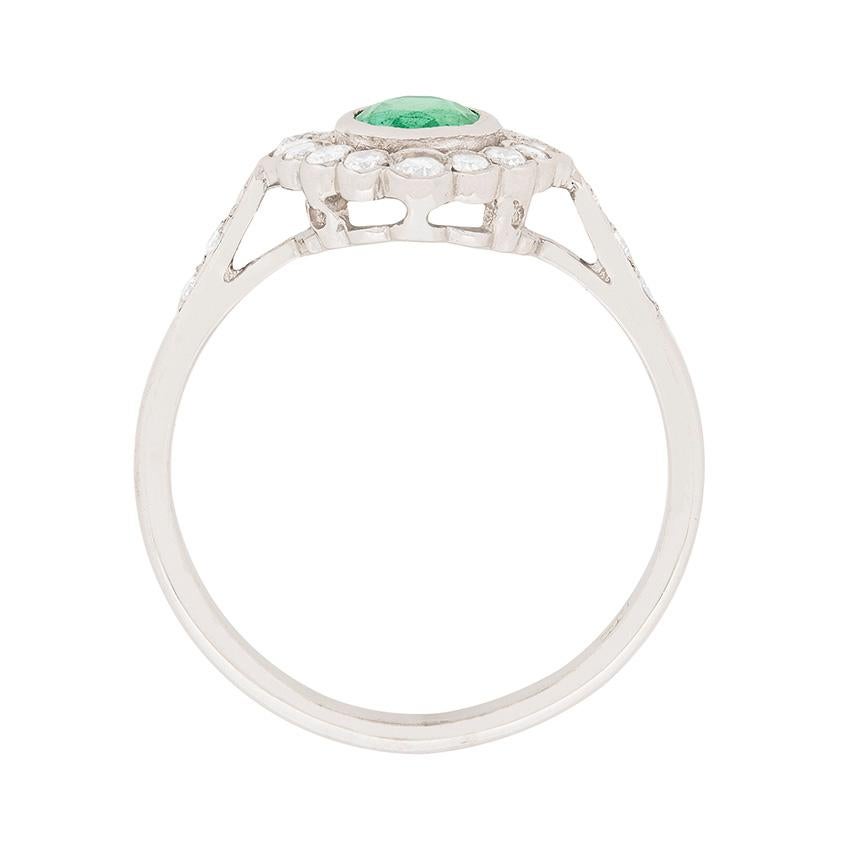 This unique ring features a rub over set emerald in the middle weighing 0.85 carat. It is a lovely green colour and is surrounded by a halo of old cut diamonds. The diamonds have a combined weigh 0.68 carat and are estimated as G in colour and VS in
