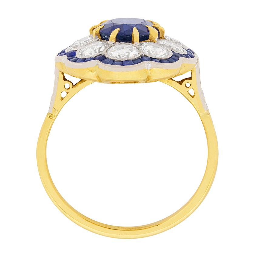 This stunning sapphire and diamond cluster ring dates to the 1940s. The centre sapphire is a wonderful deep blue colour and weighs 2.40 carat. It has been claw set using 18 carat yellow gold. Surrounding is a halo of round brilliant diamonds, ten in