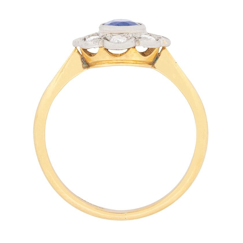 This classic and timeless sapphire ring is a daisy cluster shape with rub over set stones. The deep blue sapphire weighs 0.50 carat and is surrounded by shining diamonds weighing 0.40 carat in total. The diamonds, which are transitional cut