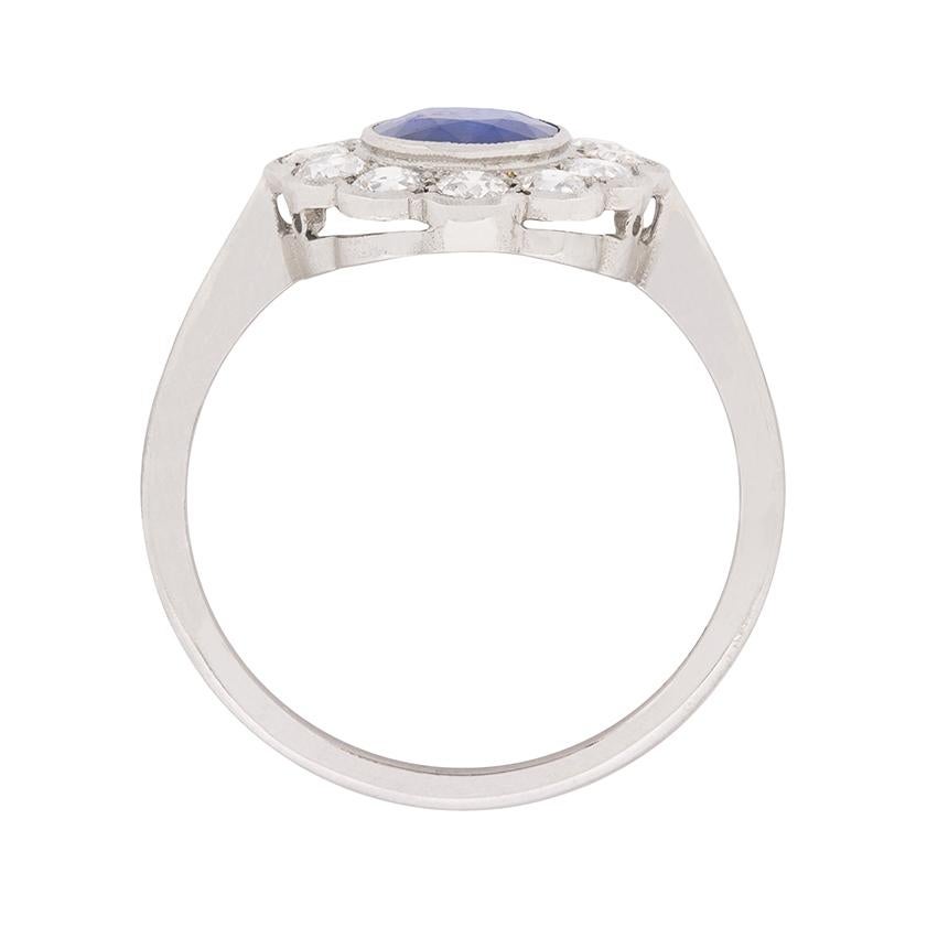 This beautiful cluster ring features a sea-blue sapphire in centre weighing 1.30 carat. It is a natural stone within a rub over setting, and haloed perfectly by shining diamonds. They are scalloped are have a combined weight of 1.20 carat, F in