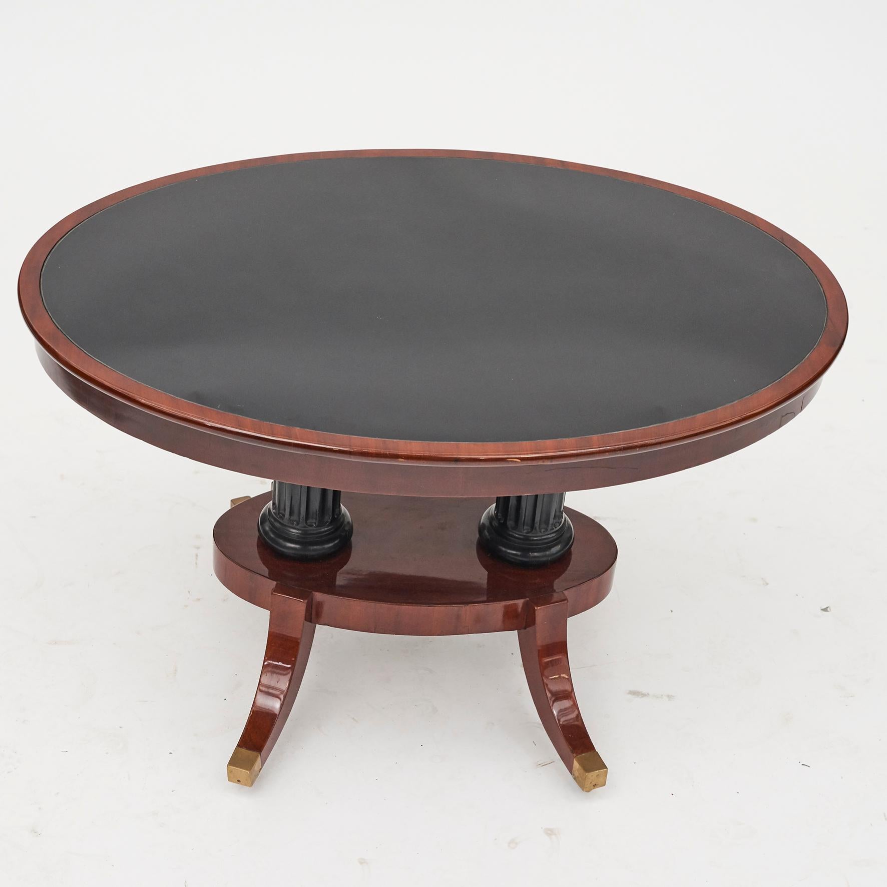 Elegant oval Danish center table, mahogany.
Tabletop with black glass.
Lower part with 2 ebonized columns, 4 legs with brass shoes and wheels.
Late Empire, Denmark, 1820-1830.