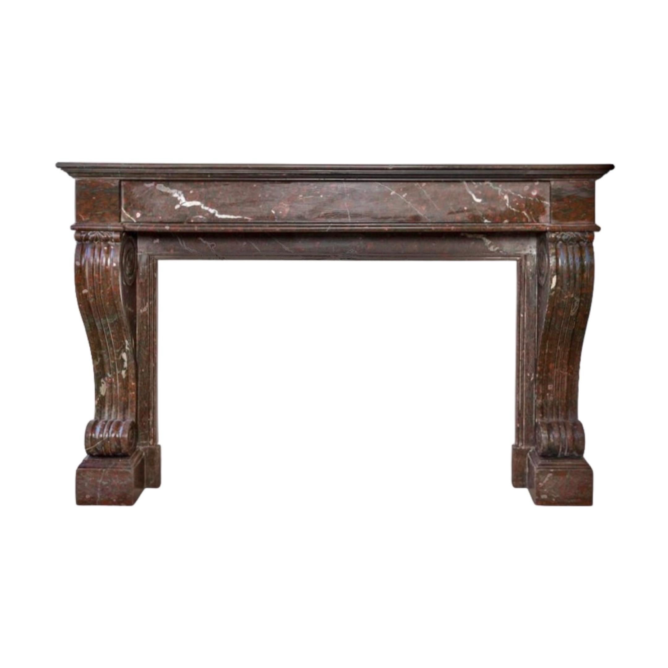 This elegant French Marble Mantel is an antique piece, originating from France circa 1820. Crafted from Red Griottee marble, this late Empire carved mantel features a generous S-scroll fluted pediment, and is supported by square block feet. A