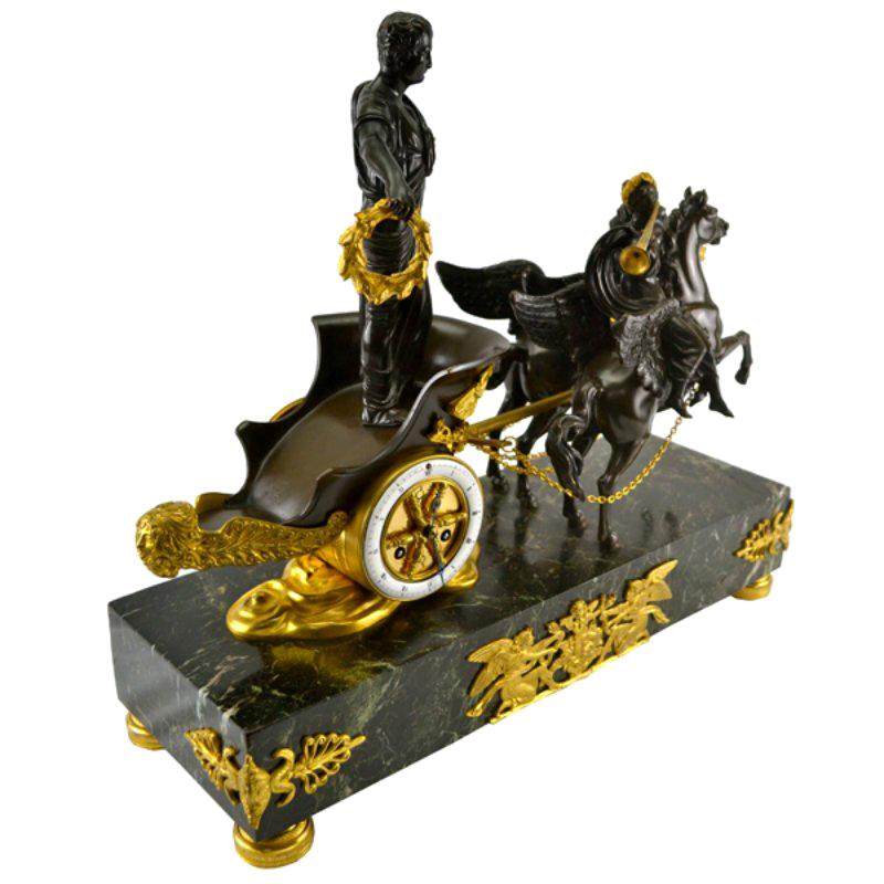 A patinated bronze figure of Caesar, (or a marshal, or general) is standing in a chariot holding a gilded wreath in his outstretched hand. The chariot with a large gilded eagle across the front is being drawn by two winged rearing horses; sitting