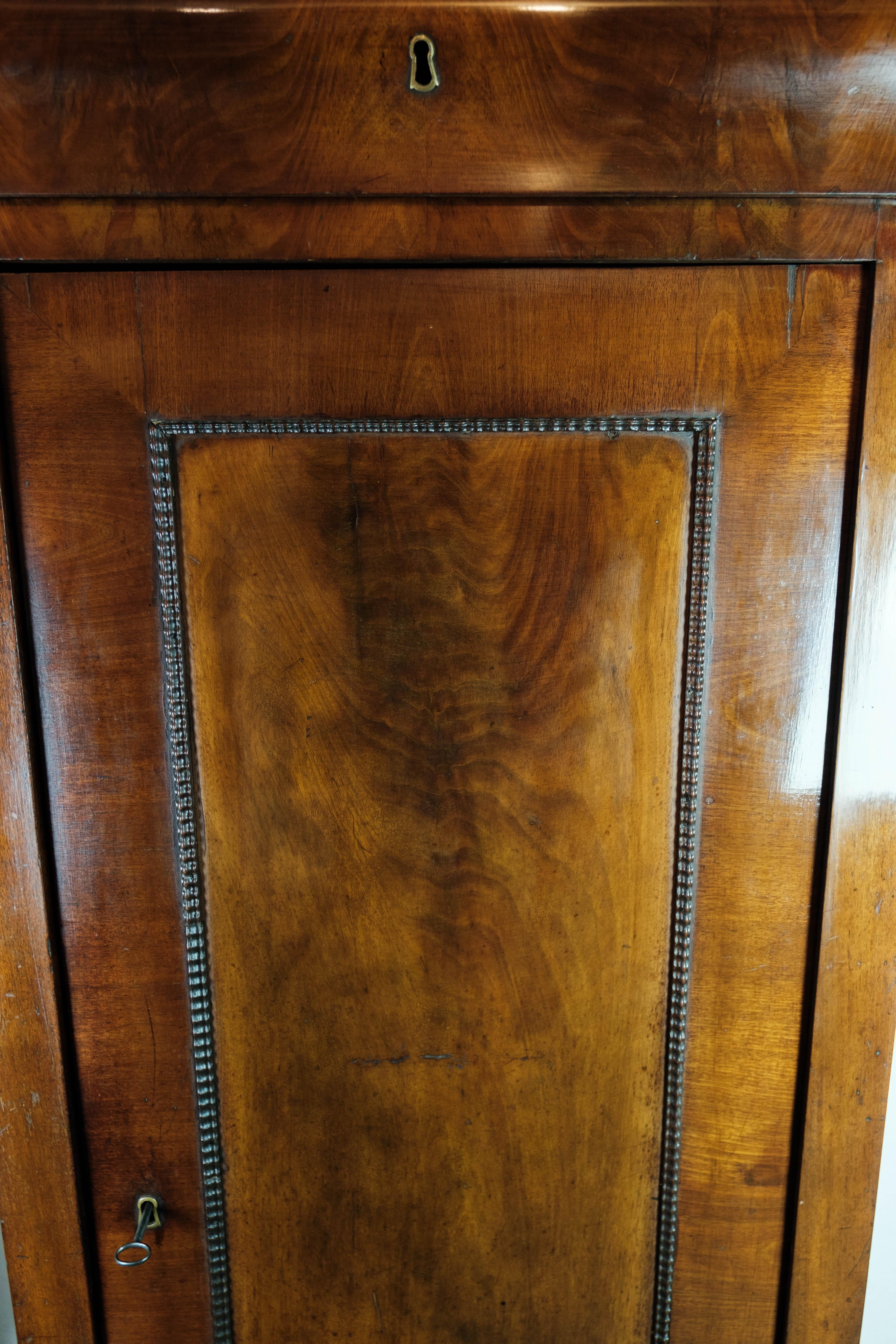 
This late Empire tall cabinet, crafted from dark polished mahogany, is a stunning example of 19th-century craftsmanship. Dating back to 1840, it stands as a testament to the elegance and sophistication of the late Empire period.

The rich, dark