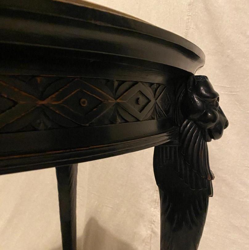 An ebonized English walnut center table in the ‘Egyptian Style” of the late Empire period.  Four elongated lion legs resting atop Ivory spheres, support an inset marble top of honed limestone.  The carved base paws are extremely well delineated as