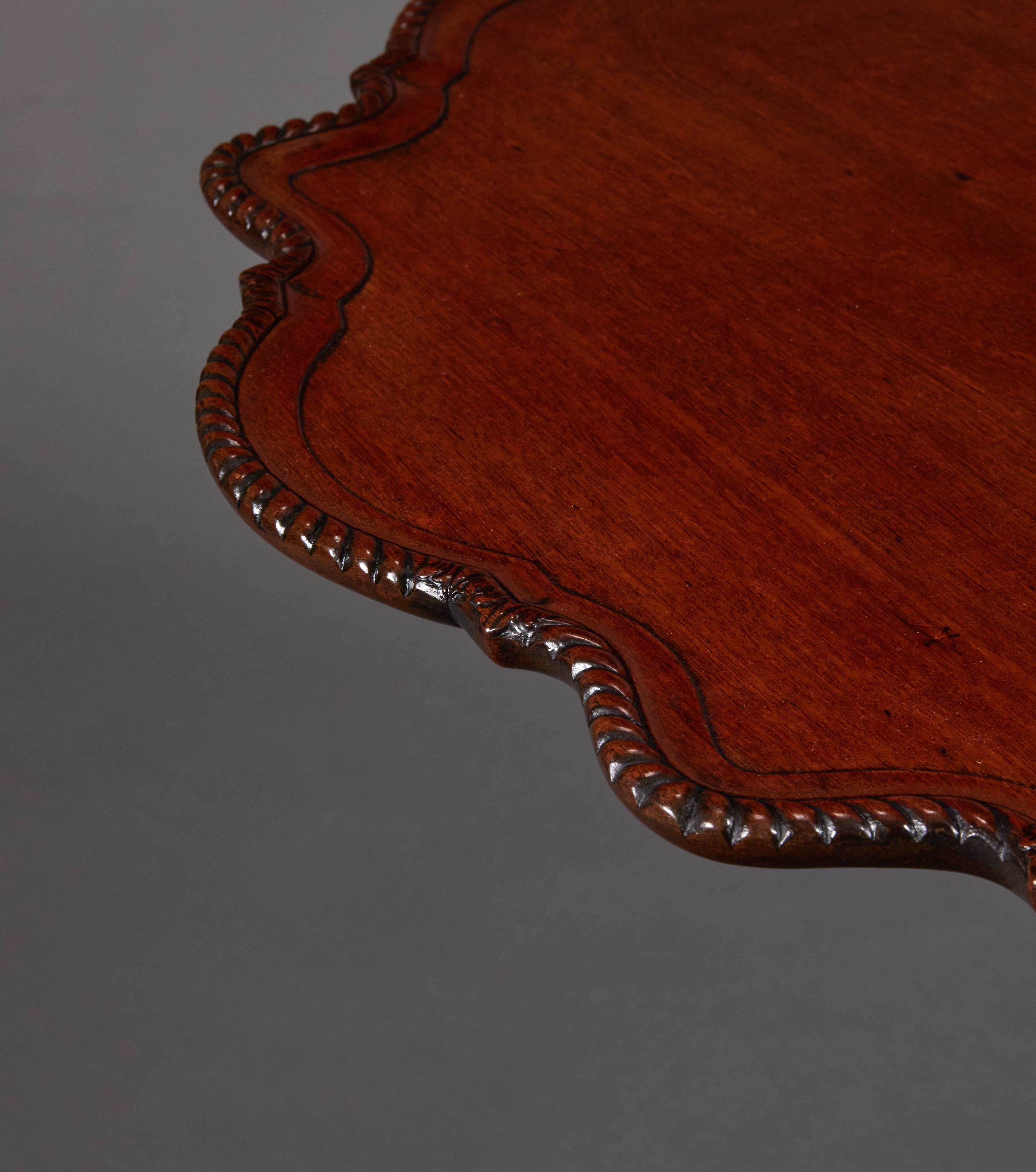 Dished-top with gadrooned edges raised on a birdcage support with fluted stem and carved cabriole legs and feet. Tilt-top folds to one side for storage. Folded measurement: 43 1/2